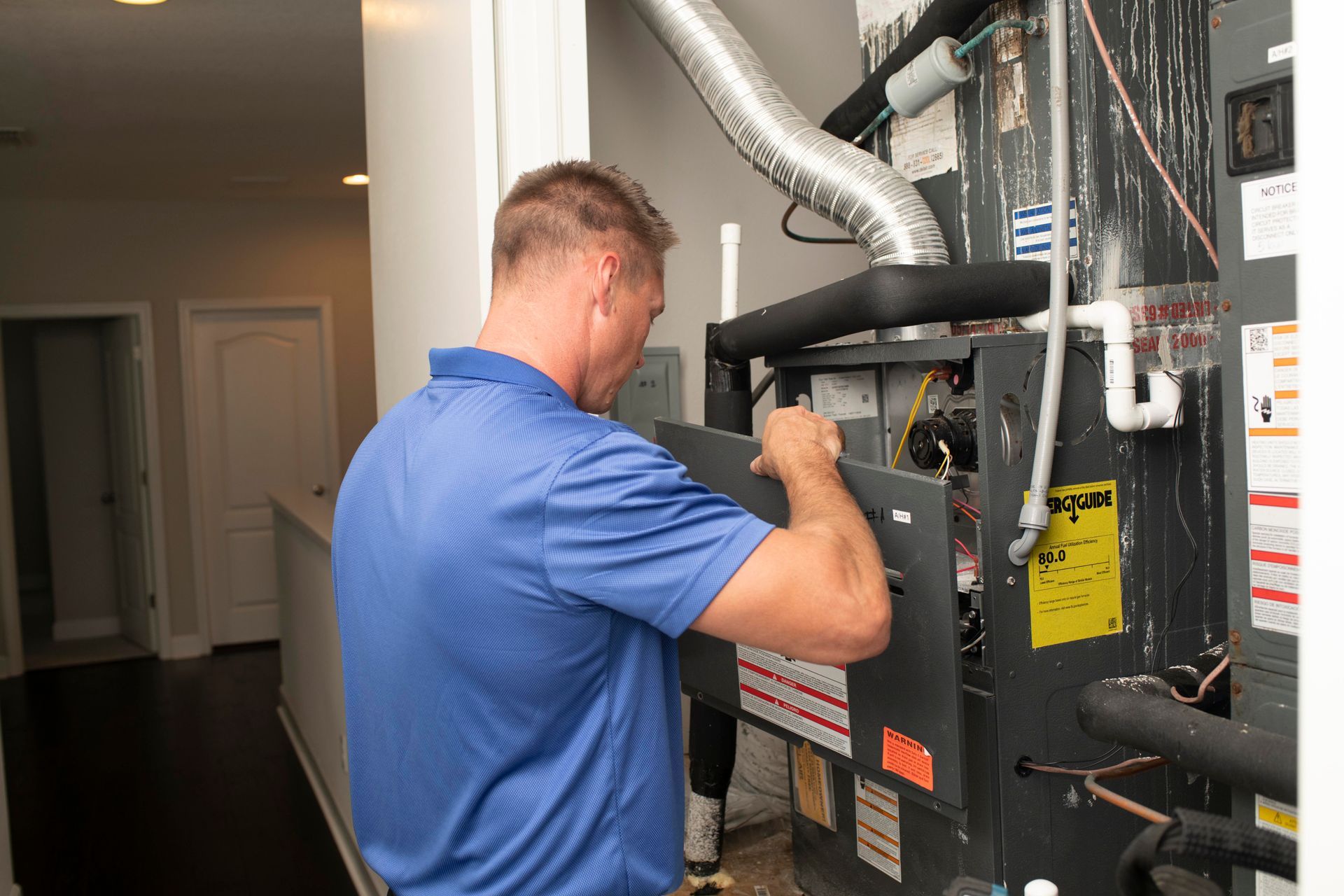 Technician inspecting a furnace or HVAC unit in a utility room