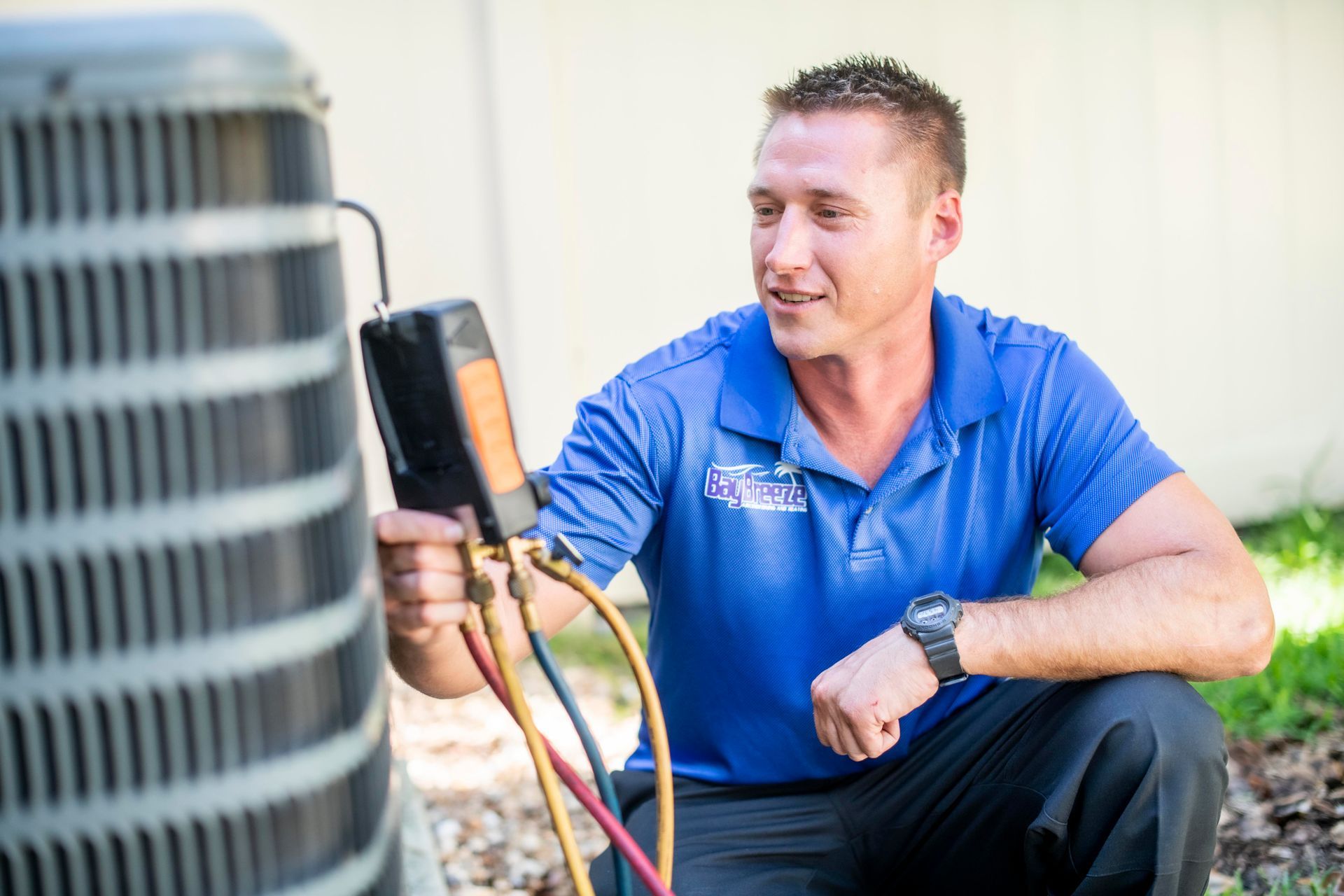 HVAC technician inspecting outdoor AC unit with gauges and tools