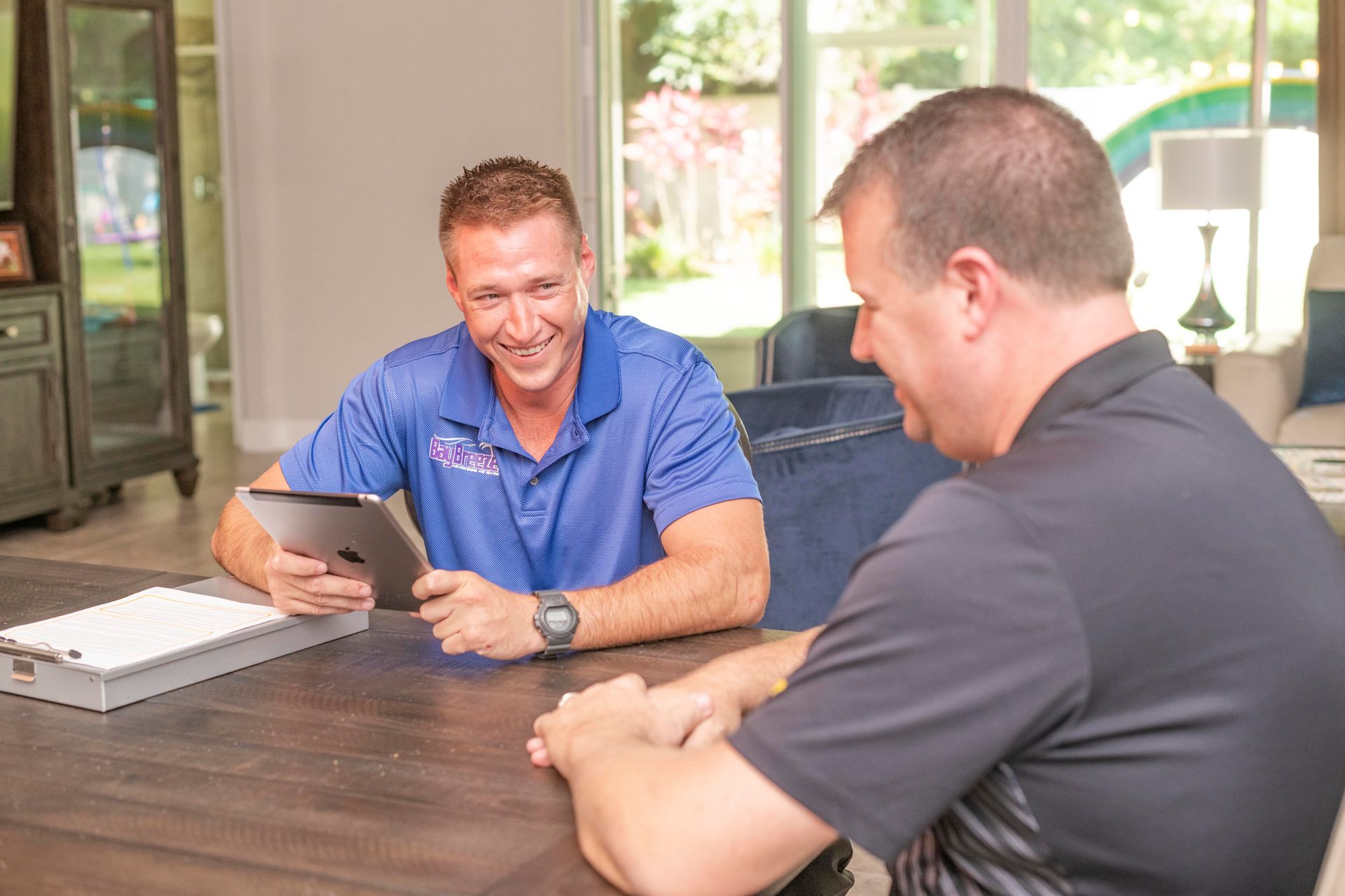 Two men smiling and talking across a table in a bright office lobby