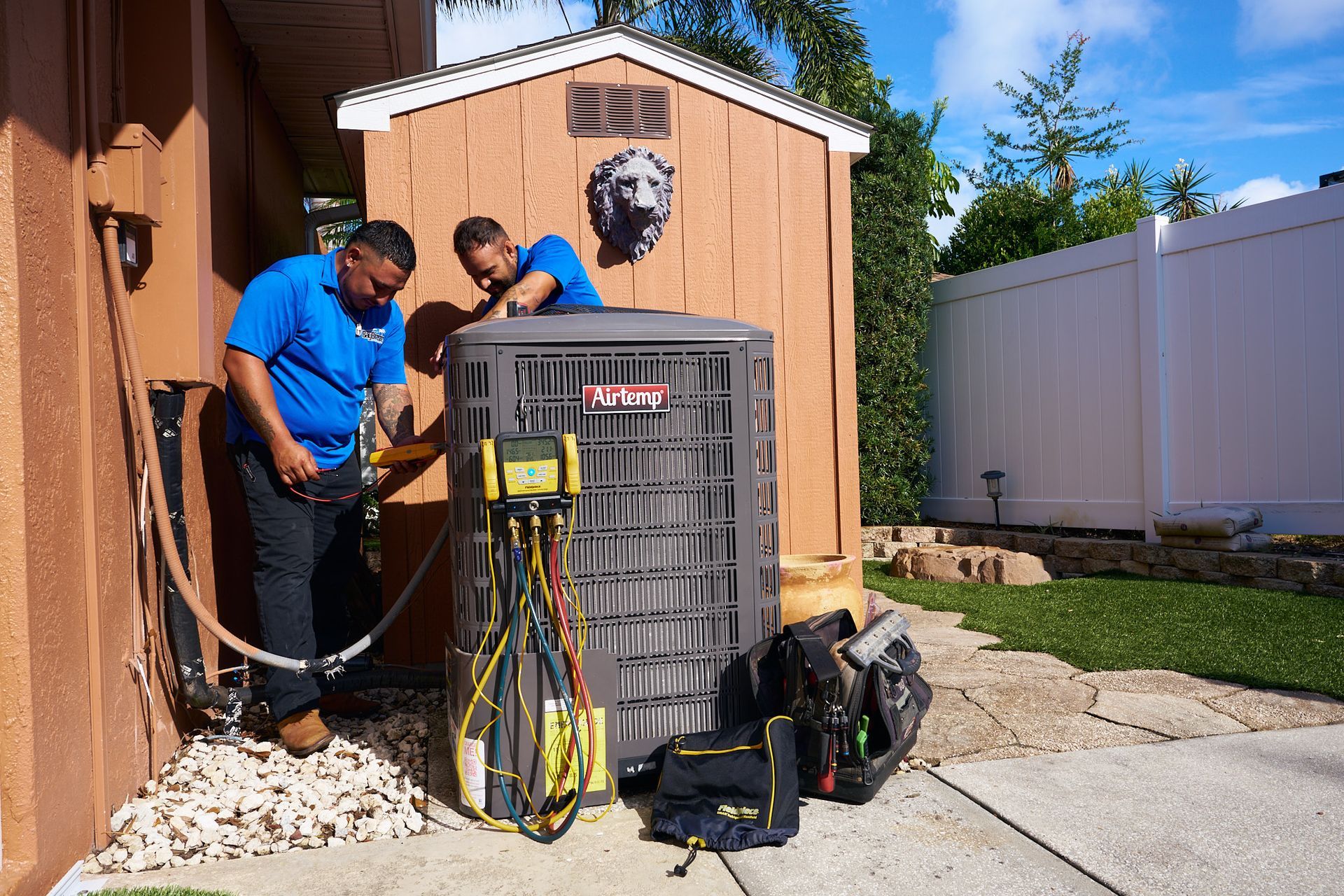 Technician in blue shirt inspecting an outdoor air conditioning unit with a gauge meter