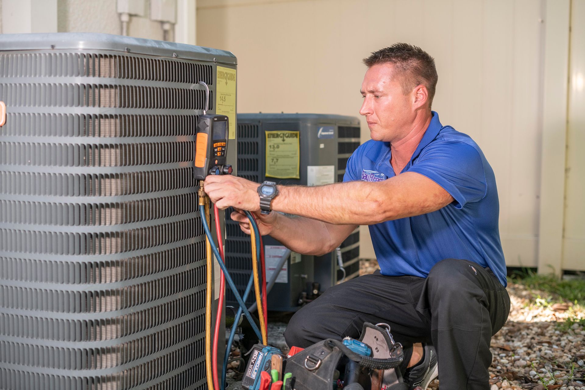 Technician inspecting an outdoor HVAC unit with gauges and tools attached