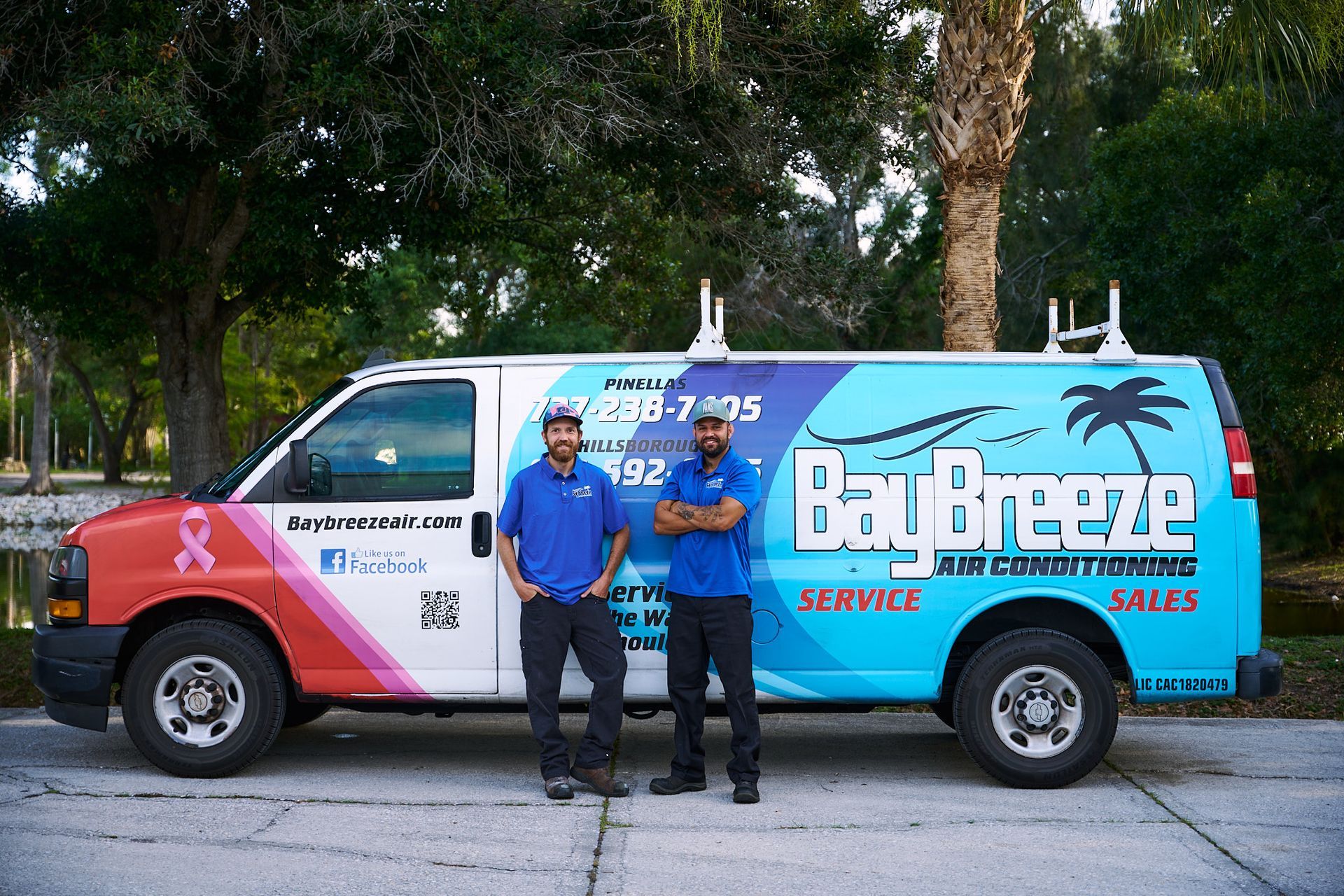 Technician in blue shirt checking an outdoor air conditioner unit with a multimeter
