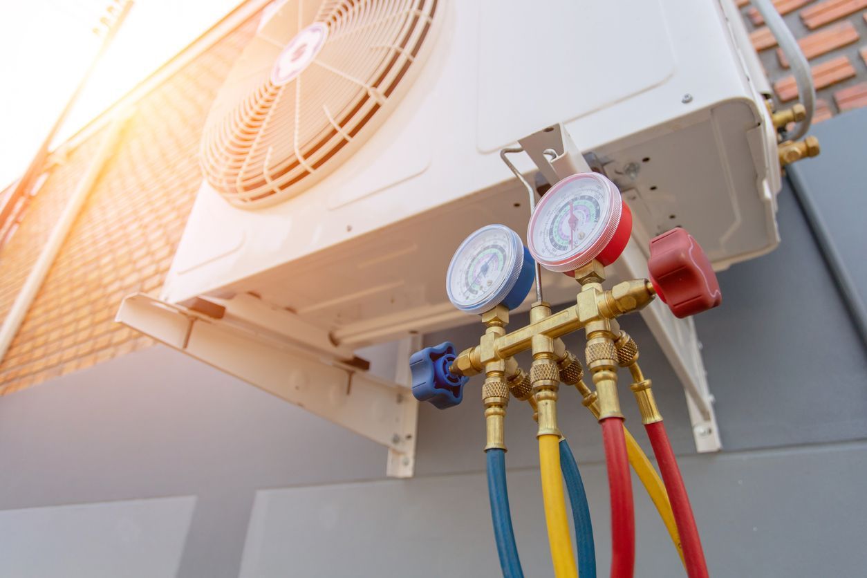 Outdoor HVAC unit with manifold gauges and color-coded refrigerant hoses attached