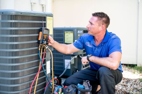 Technician using a multimeter to inspect an outdoor air conditioning unit