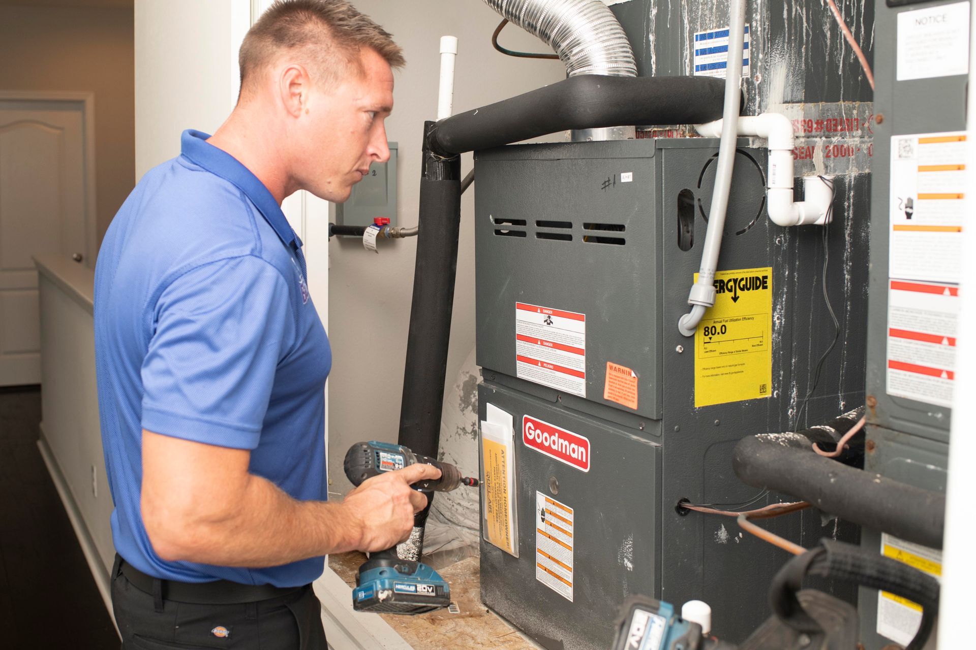 Technician inspecting a furnace in a utility room with tools in hand
