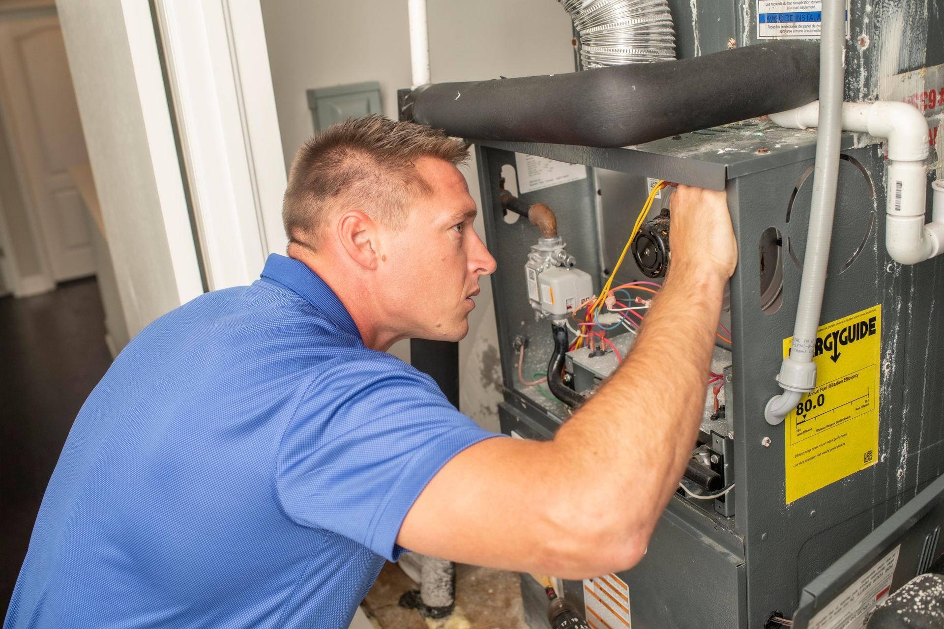 Technician inspecting an HVAC furnace with tools in a basement utility area