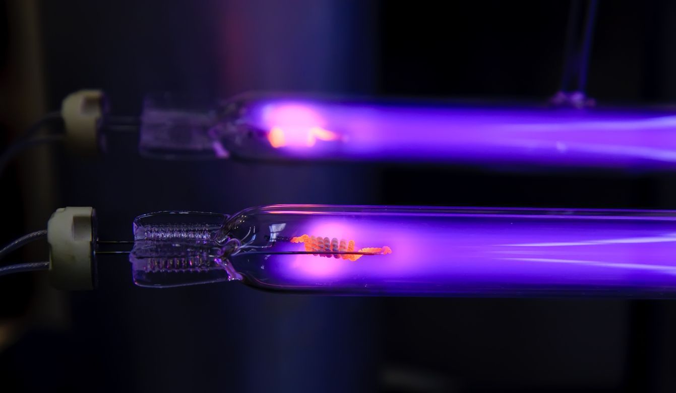 Two glowing purple plasma tubes on a black background, one with a bright spark inside
