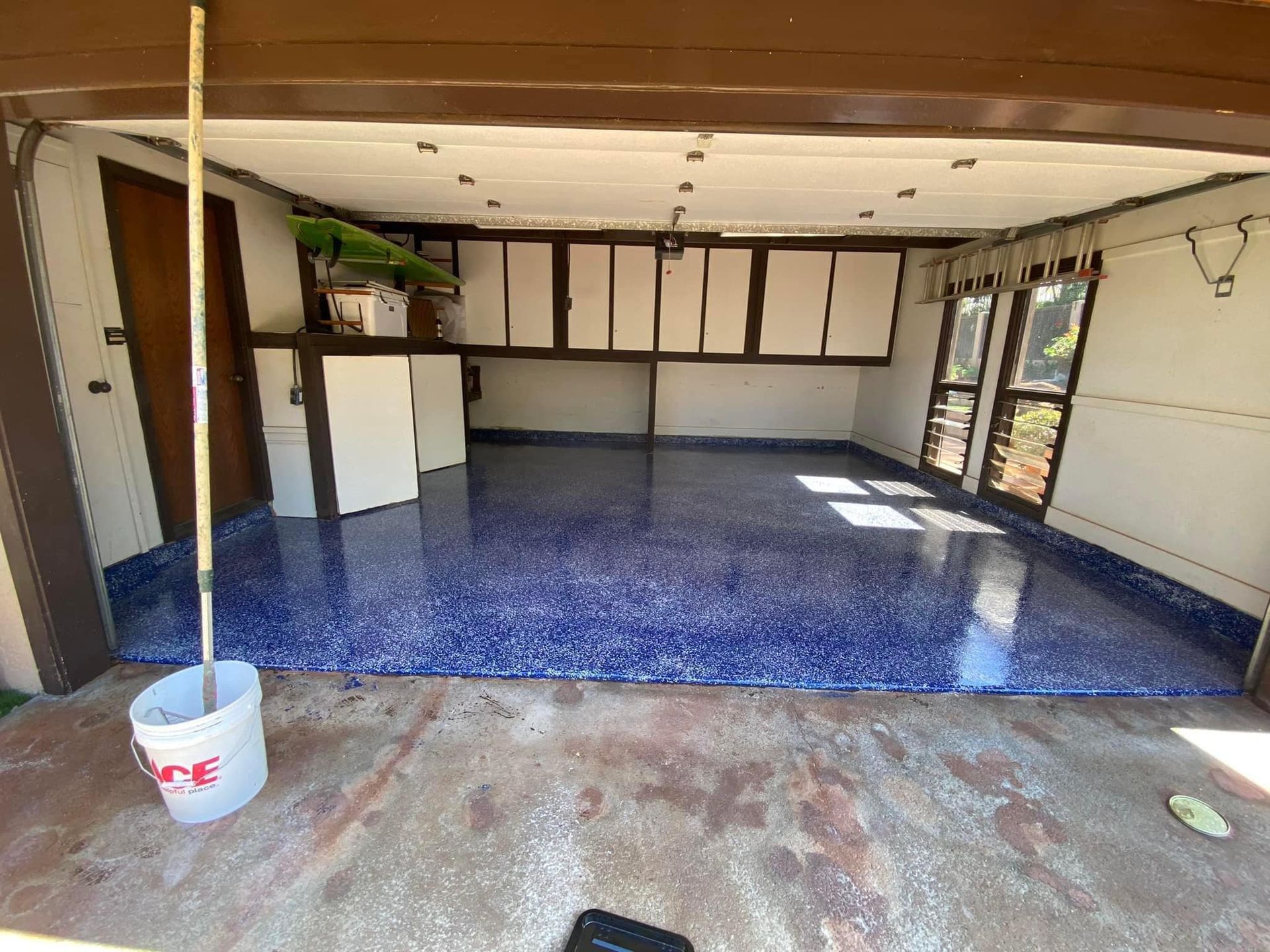 A garage with a blue floor and a mop in it.