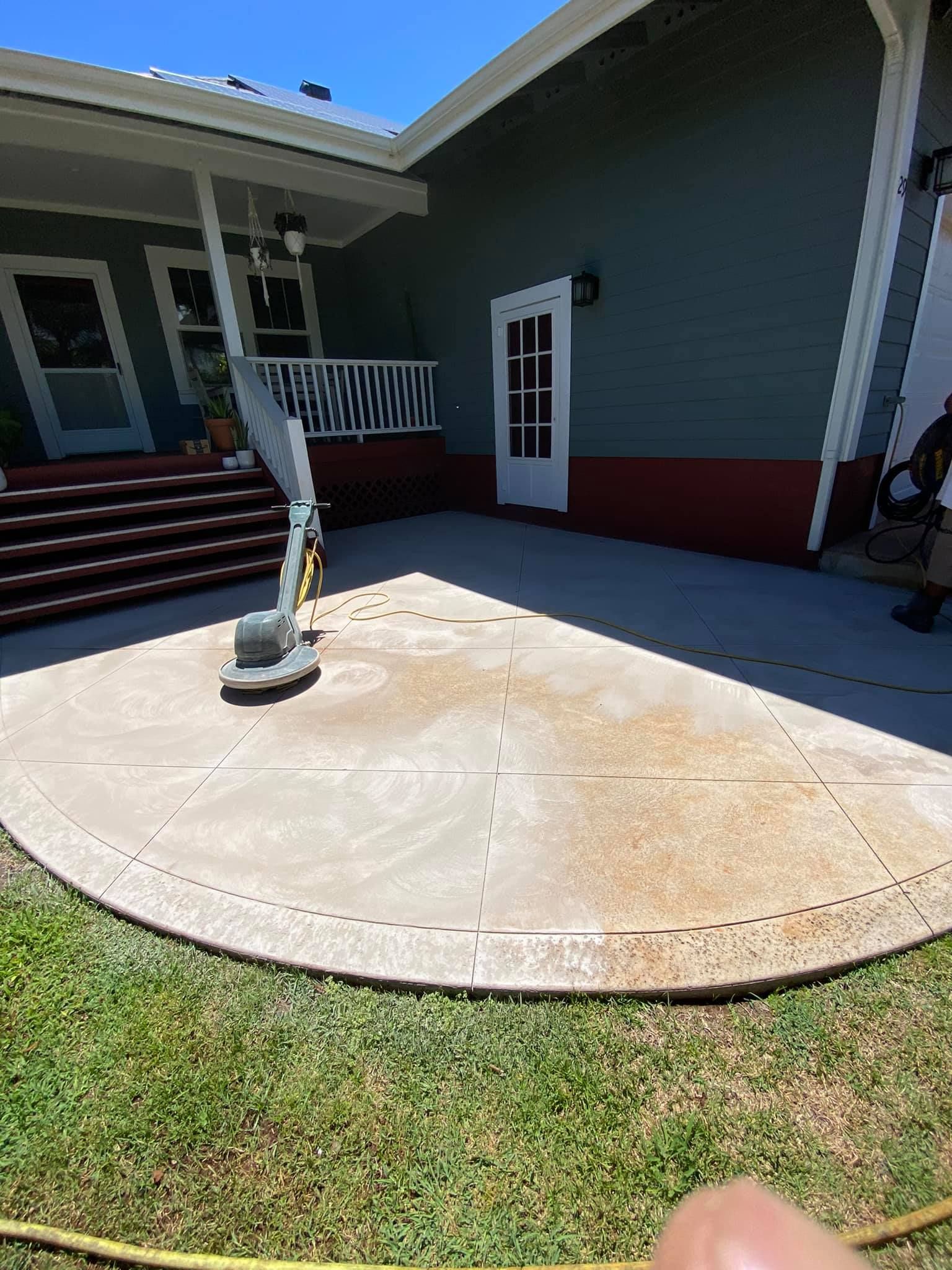 A person is cleaning a concrete patio in front of a house.