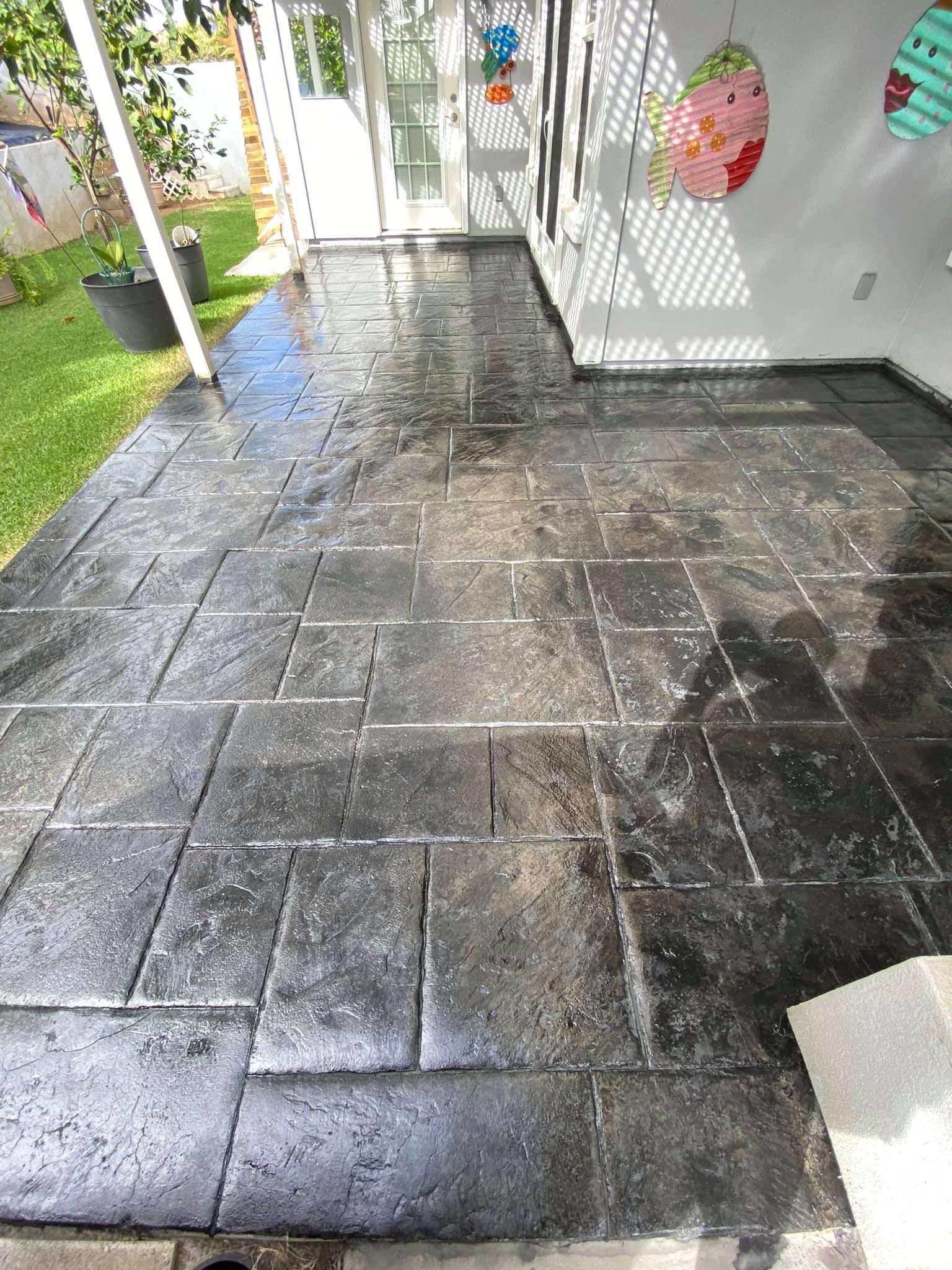 A black tiled floor in a room with a patio in the background.