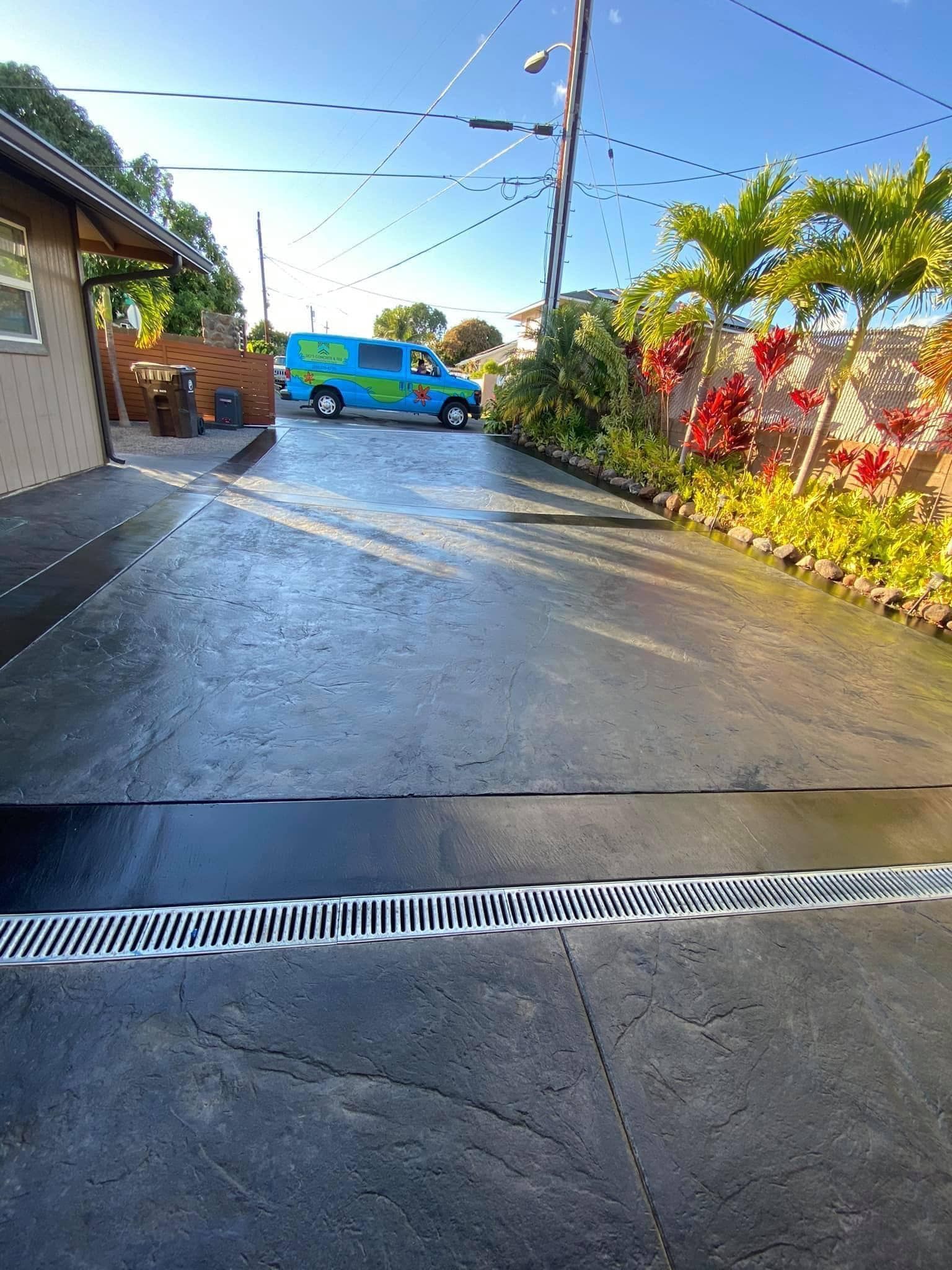 A blue van is parked in a driveway next to a house.