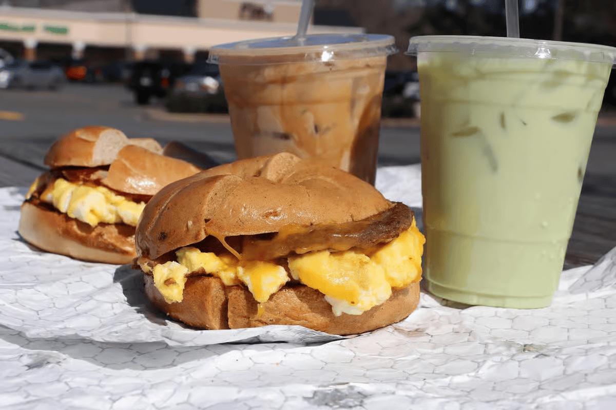 Two egg sandwiches and iced matcha and coffee drinks on a table.
