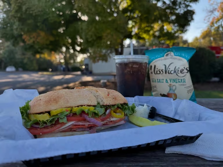 Hand holding a double scoop Oreo ice cream cone outdoors.