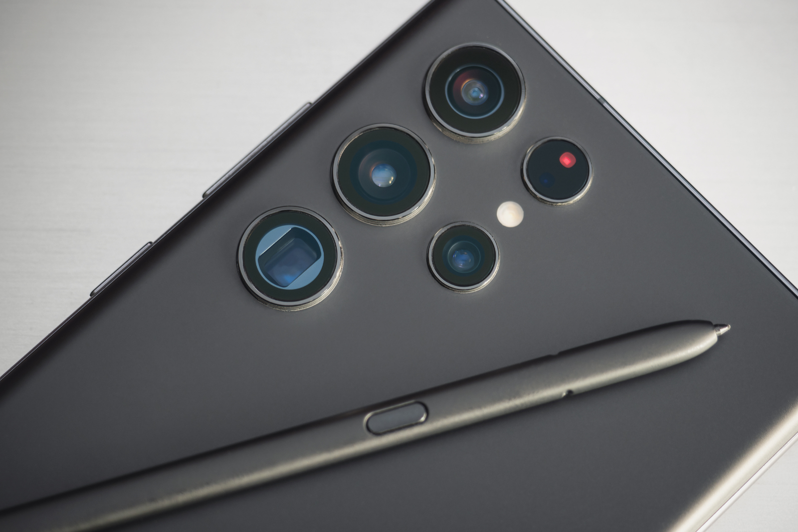 Close-up of a matte black Samsung Galaxy smartphone back, showing the multi-lens camera array and a matching stylus pen.
