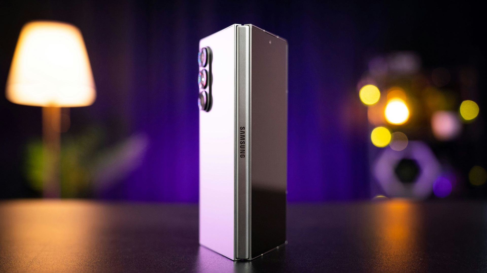 Silver smartphone standing upright on a table, with a blurred lamp and city lights in the background