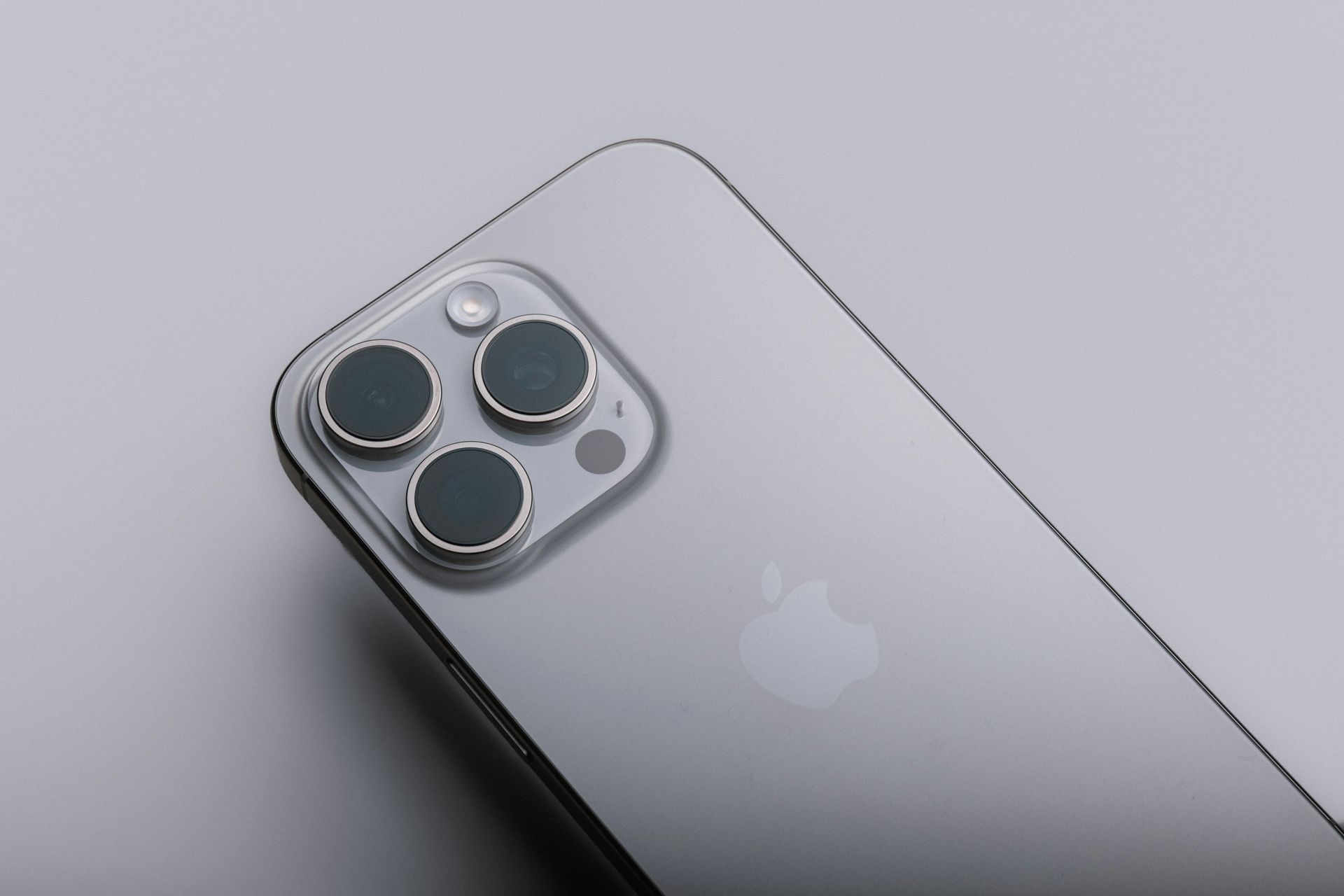 Silver iPhone with triple-camera module on a light gray background
