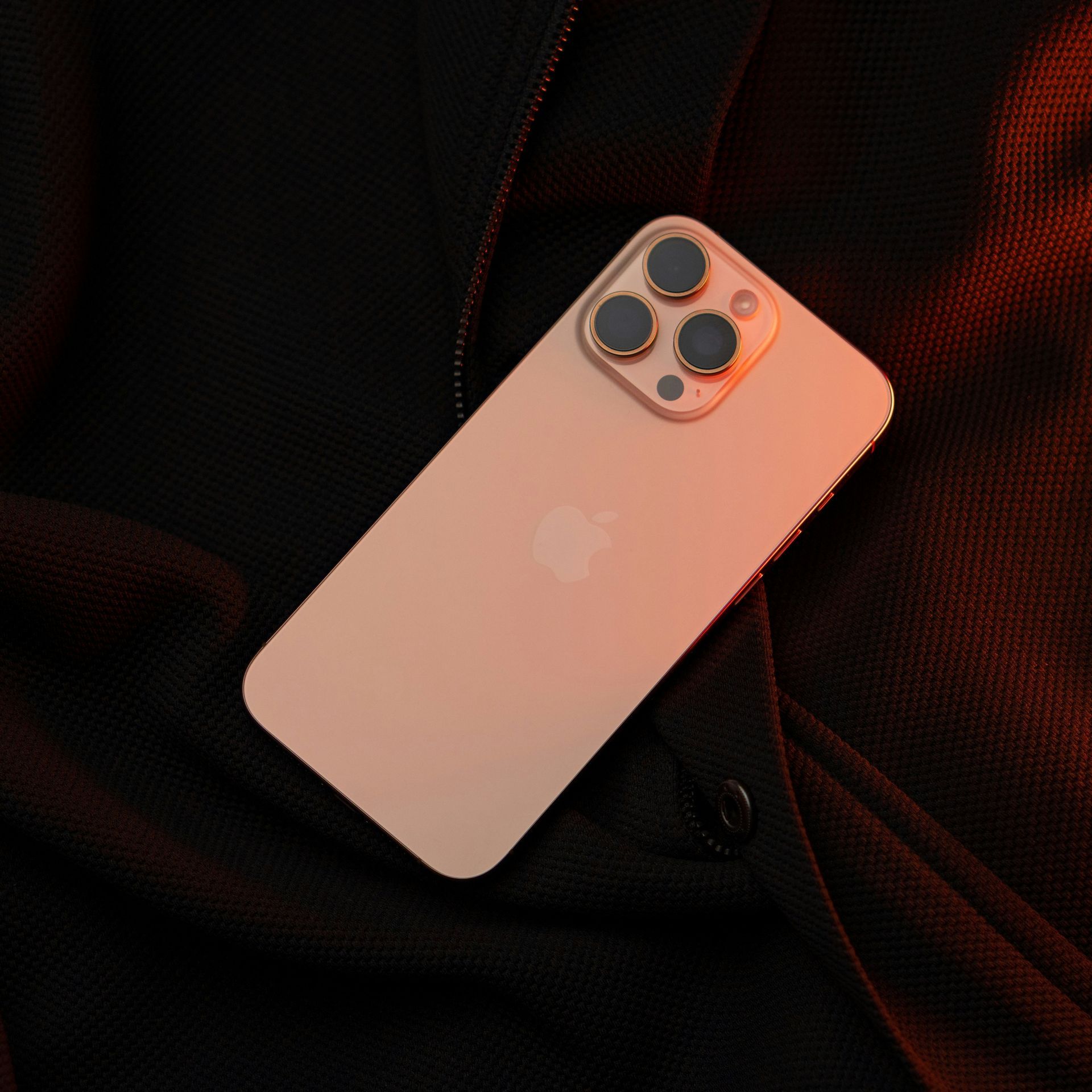 Pink iPhone with triple camera on a dark textured background
