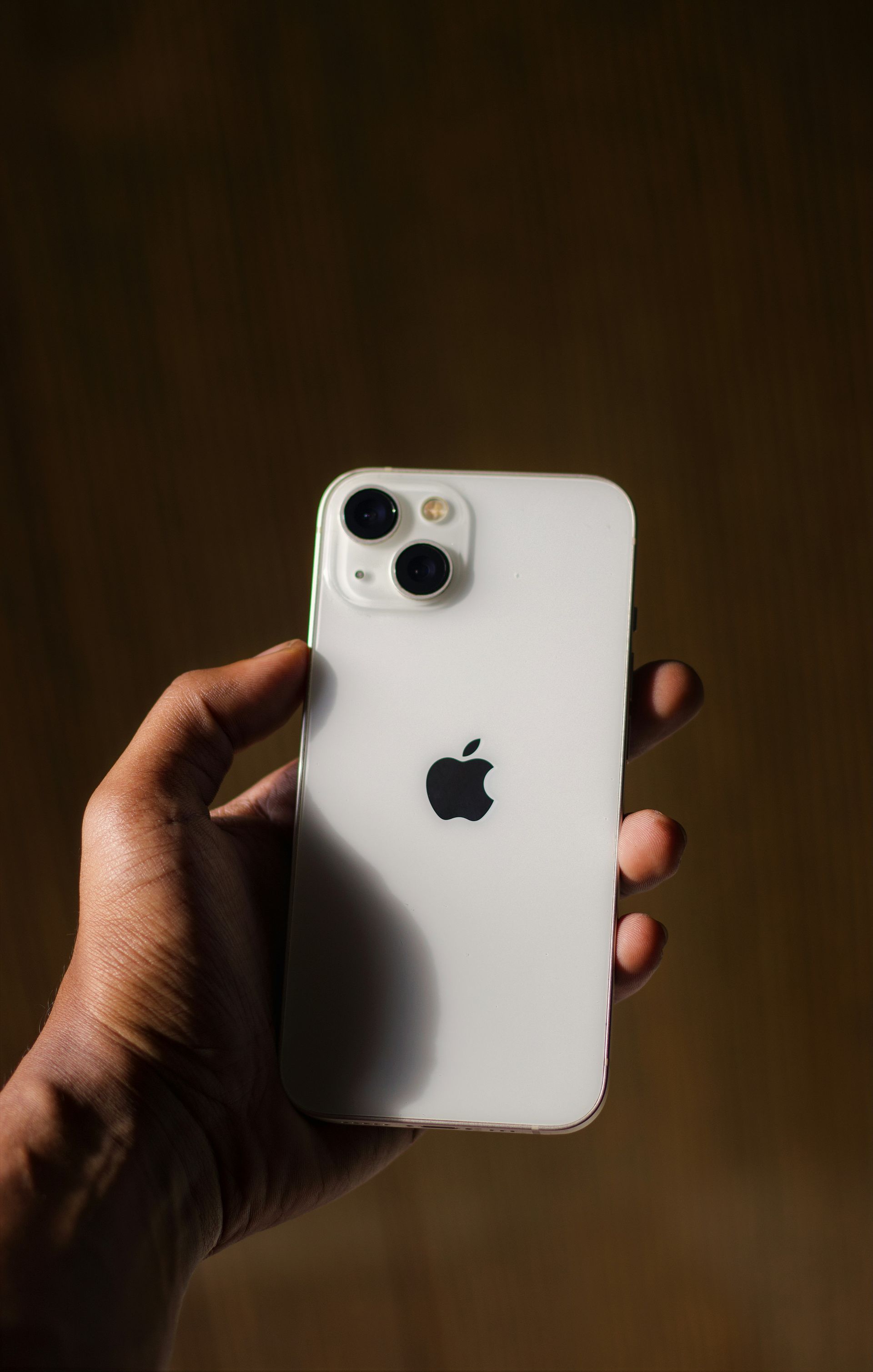 Hand holding a white iPhone against a dark background