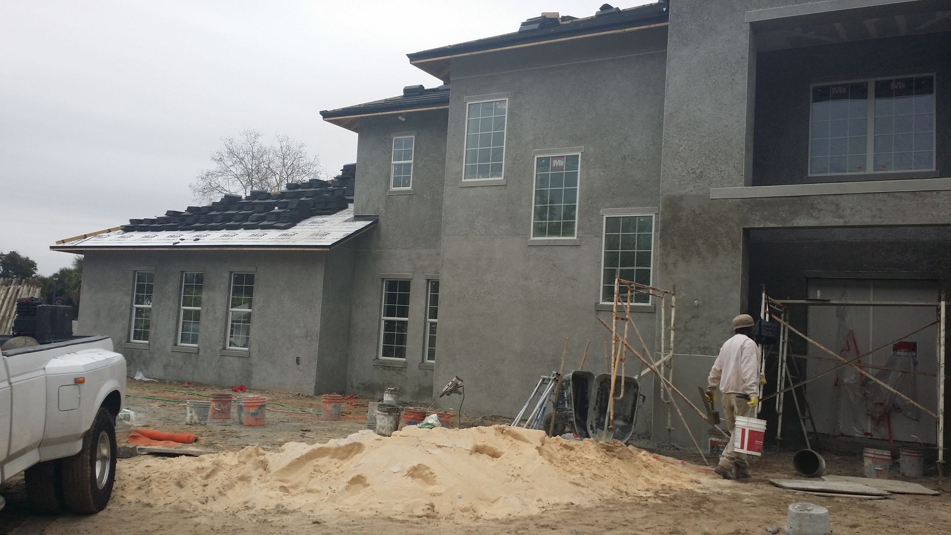 A white truck is parked in front of a building under construction