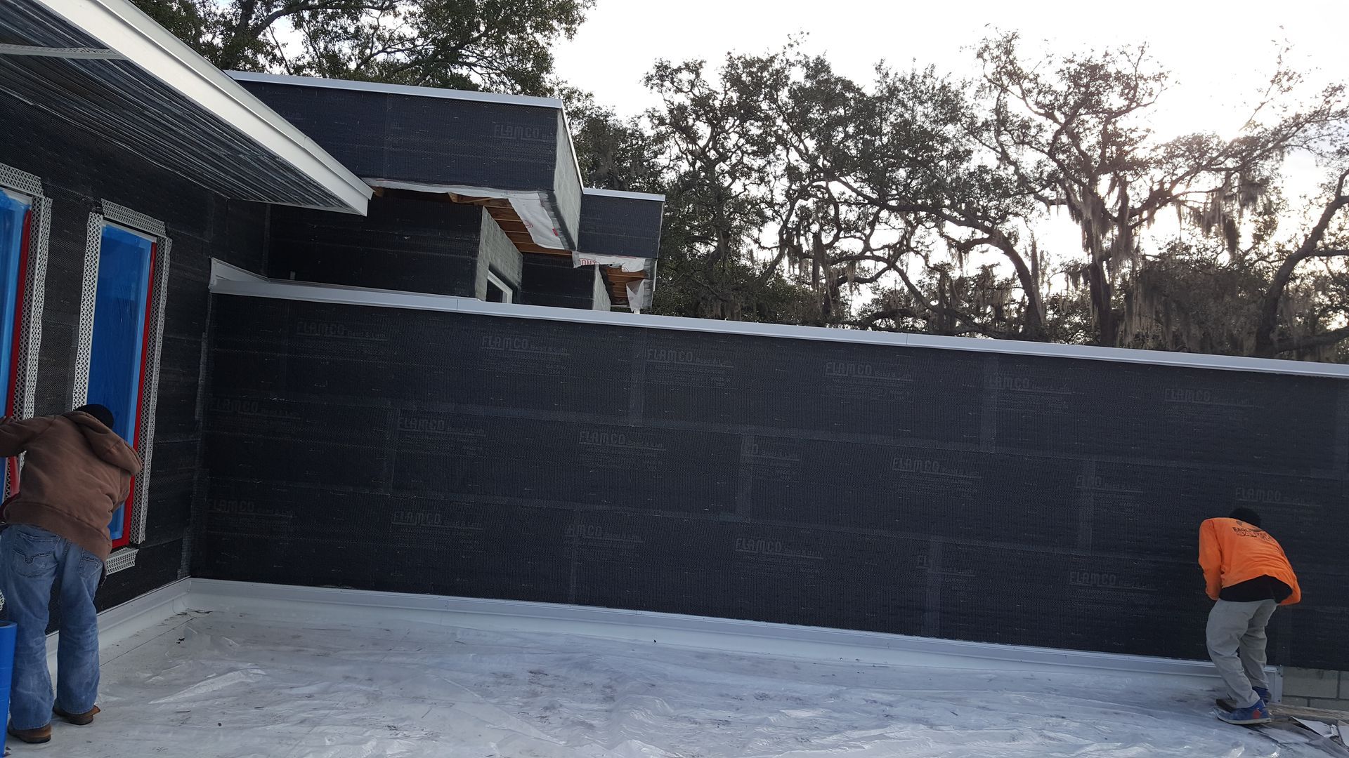 Two men are standing in front of a black wall.