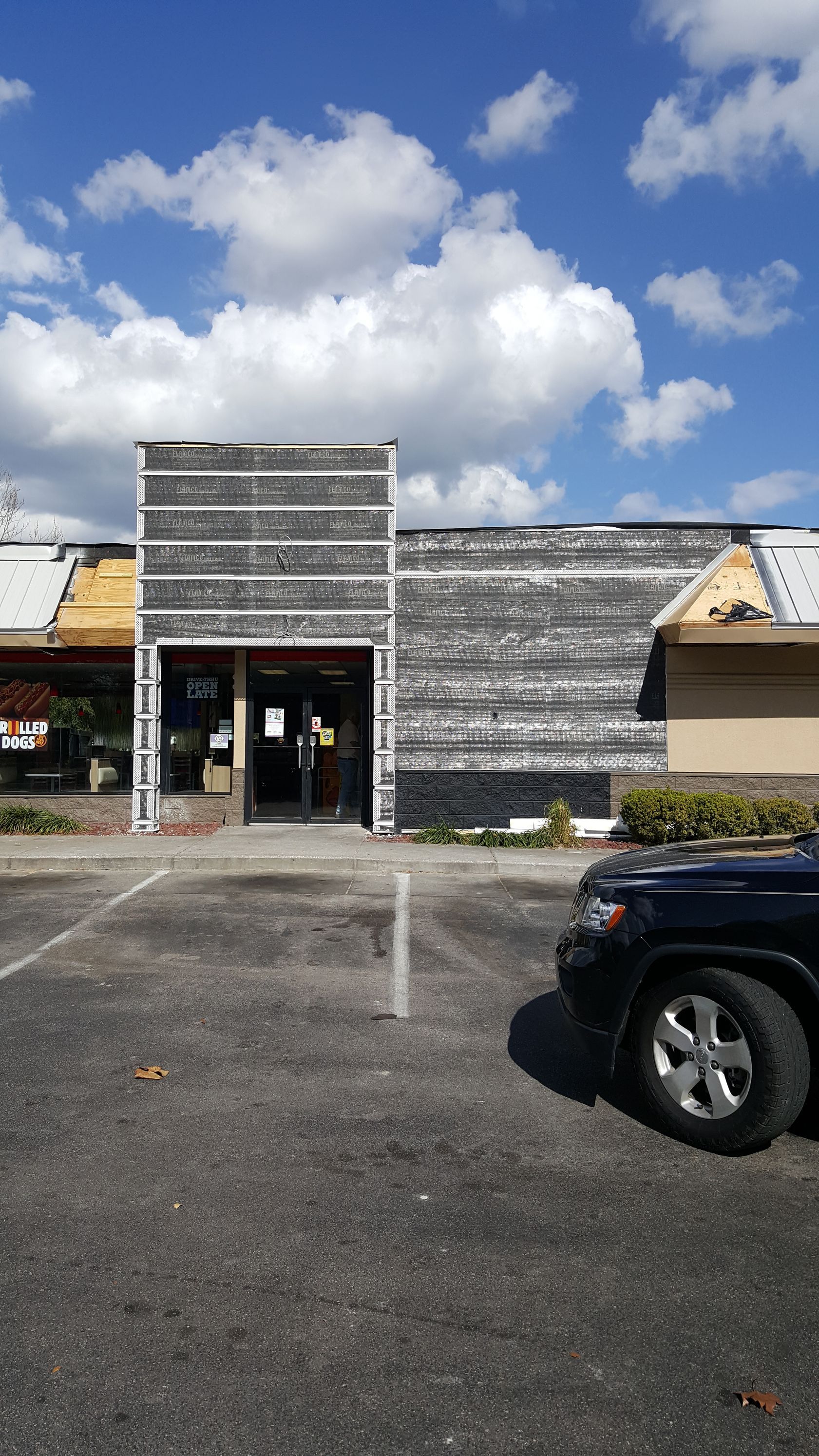 A car is parked in front of a building that is being remodeled.