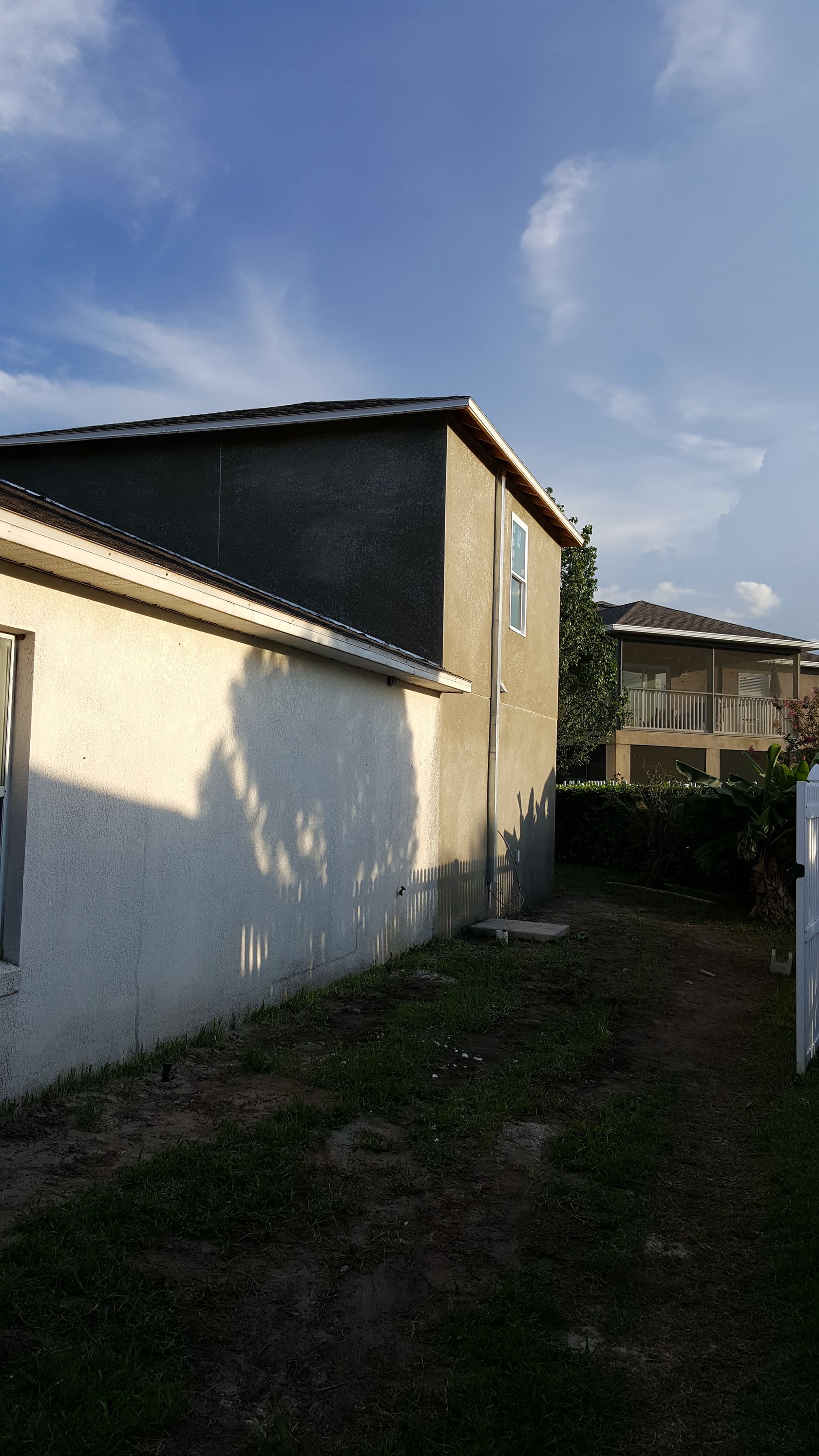 A house with a fence in front of it and a blue sky in the background.
