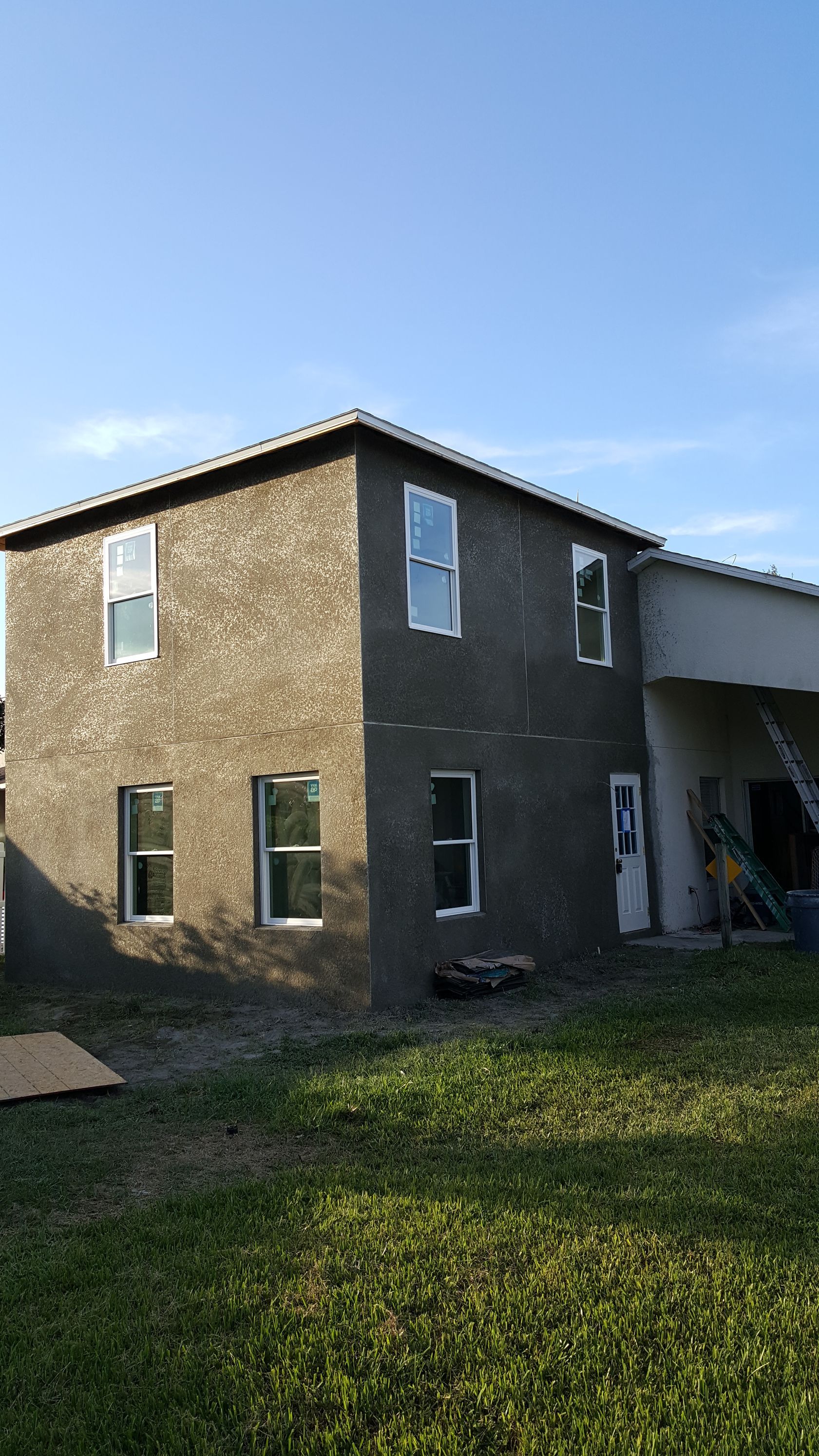 A large house with a lot of windows is sitting on top of a lush green field.