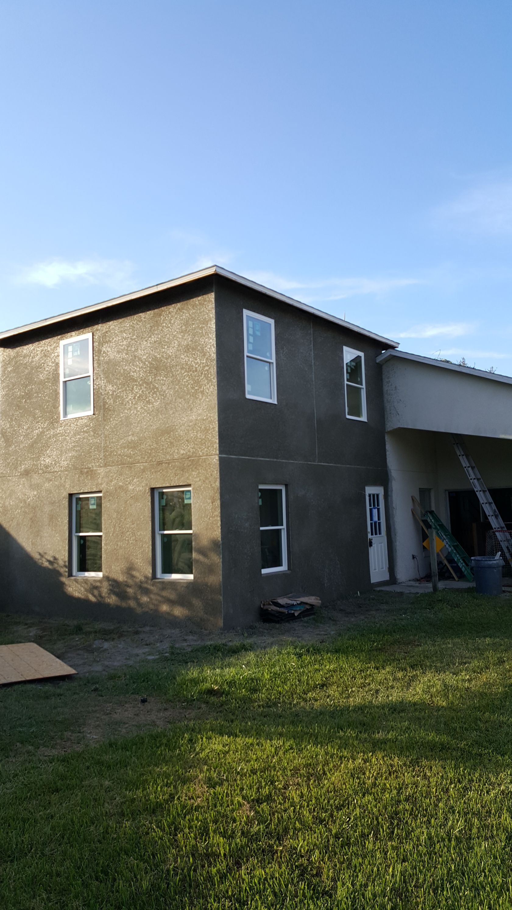 A large house with a lot of windows is sitting on top of a lush green field.