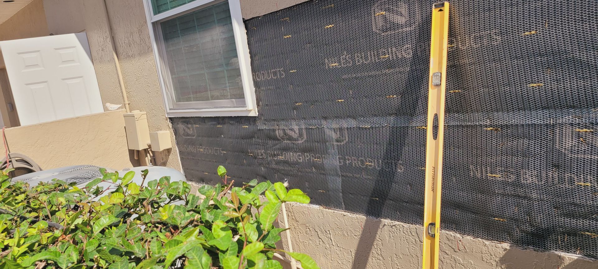 A yellow level is sitting on the side of a building next to a window.