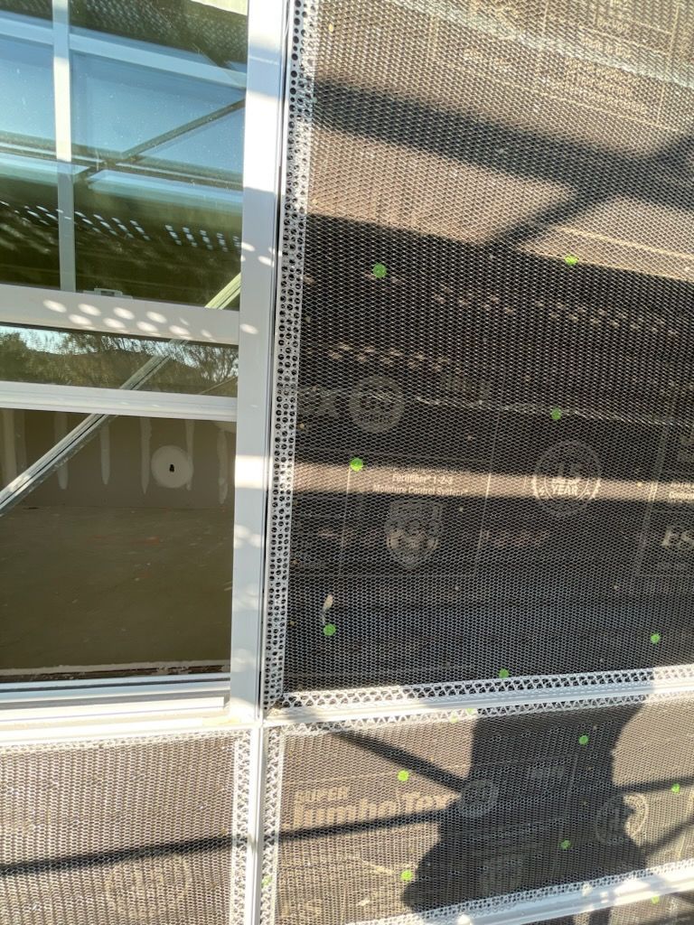 A close up of a fence with a reflection of a building in it.