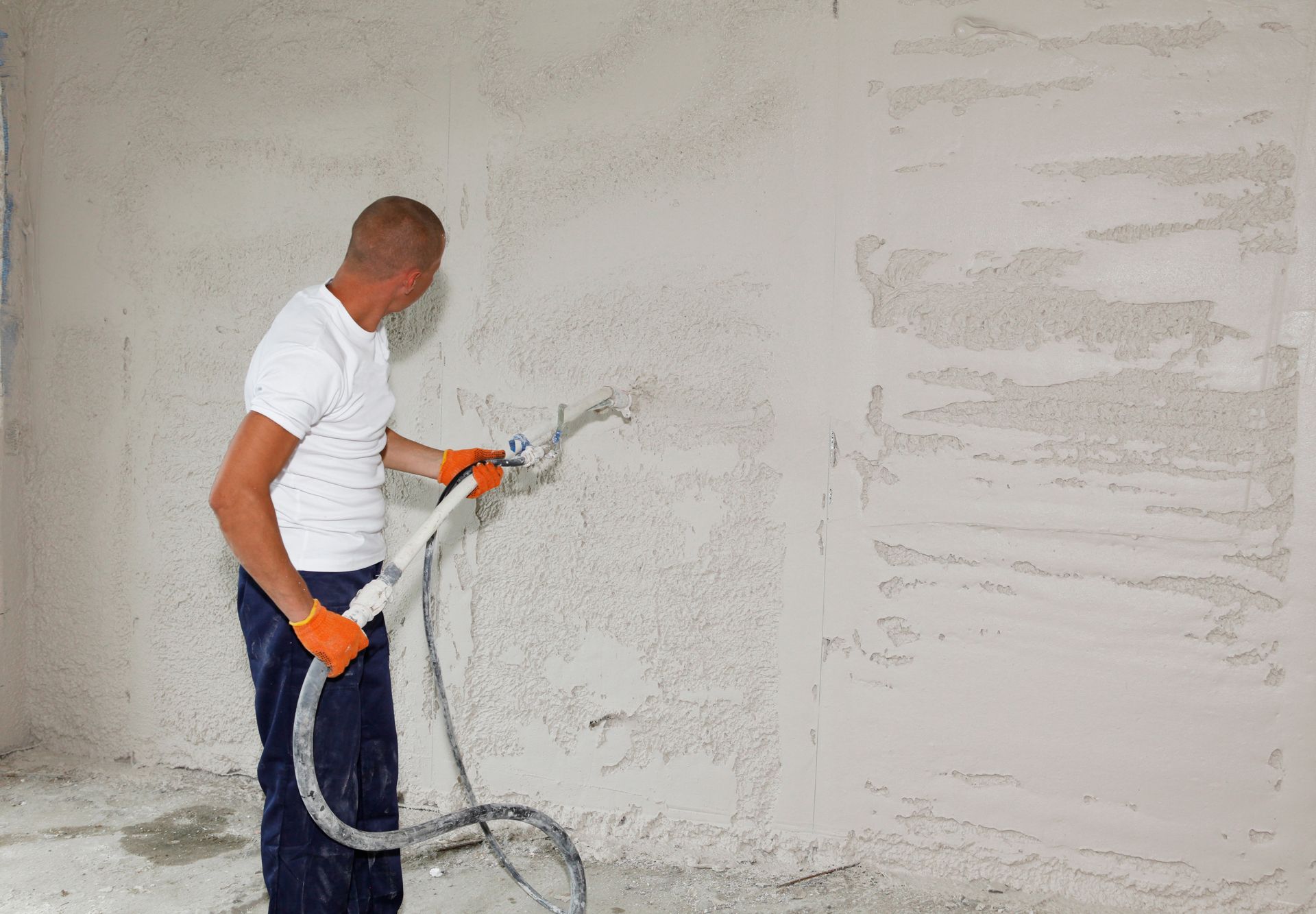 A man is plastering a wall with a hose.