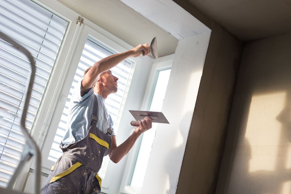 A man is plastering a wall with a spatula.