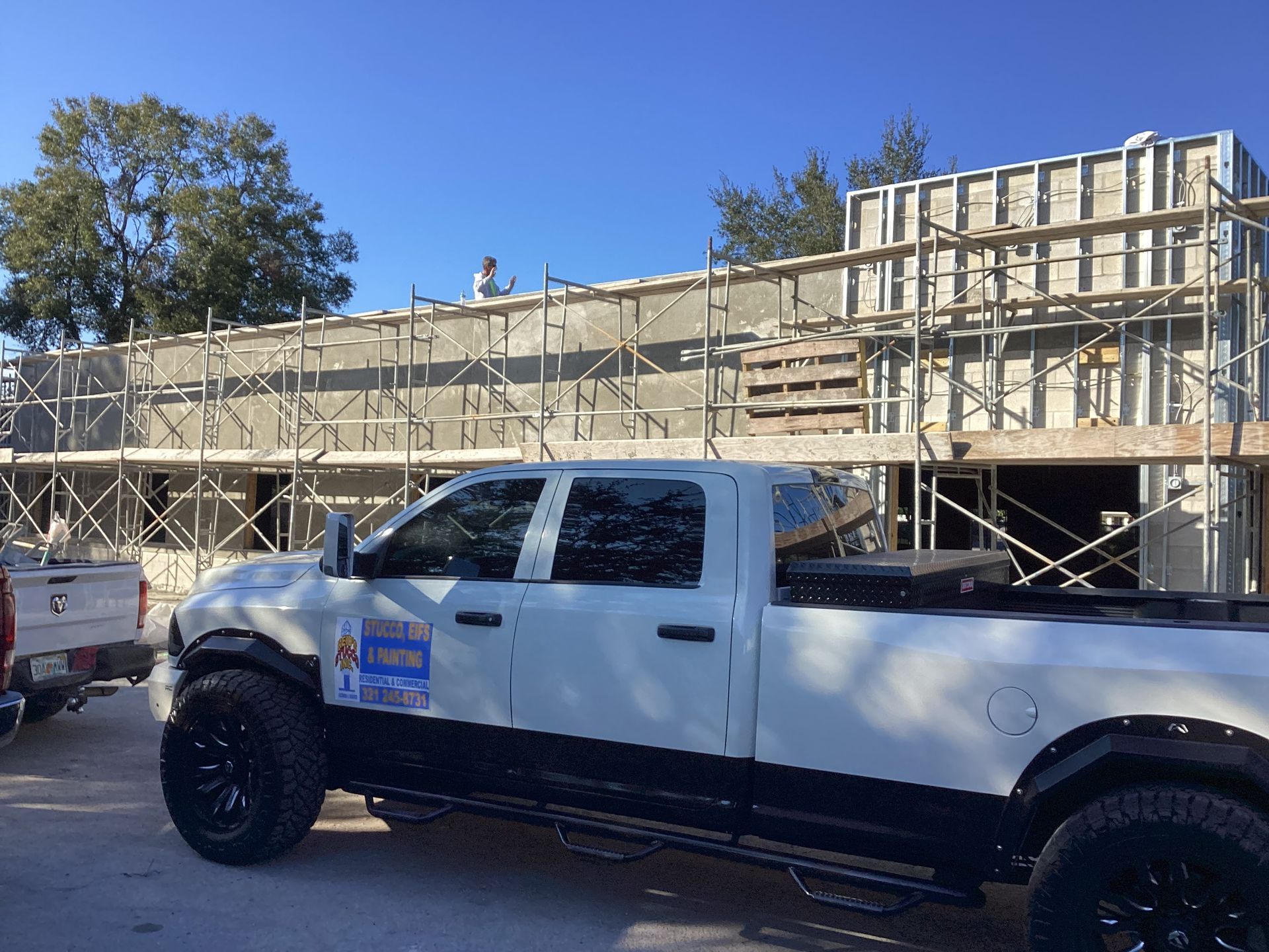 A white truck is parked in front of a building under construction.