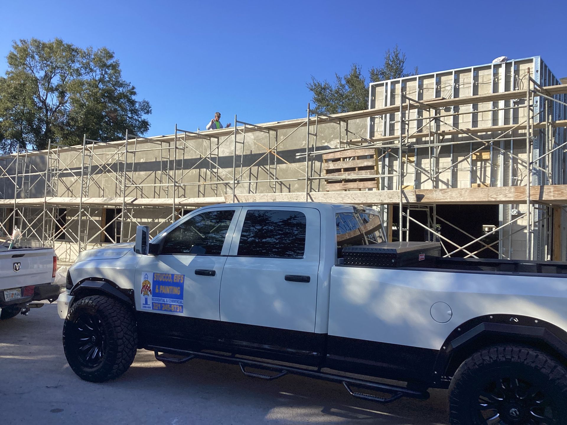 A white truck is parked in front of a building under construction.