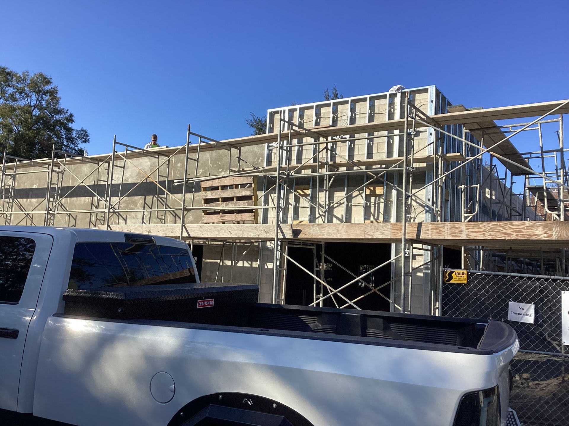 A white truck is parked in front of a building under construction.