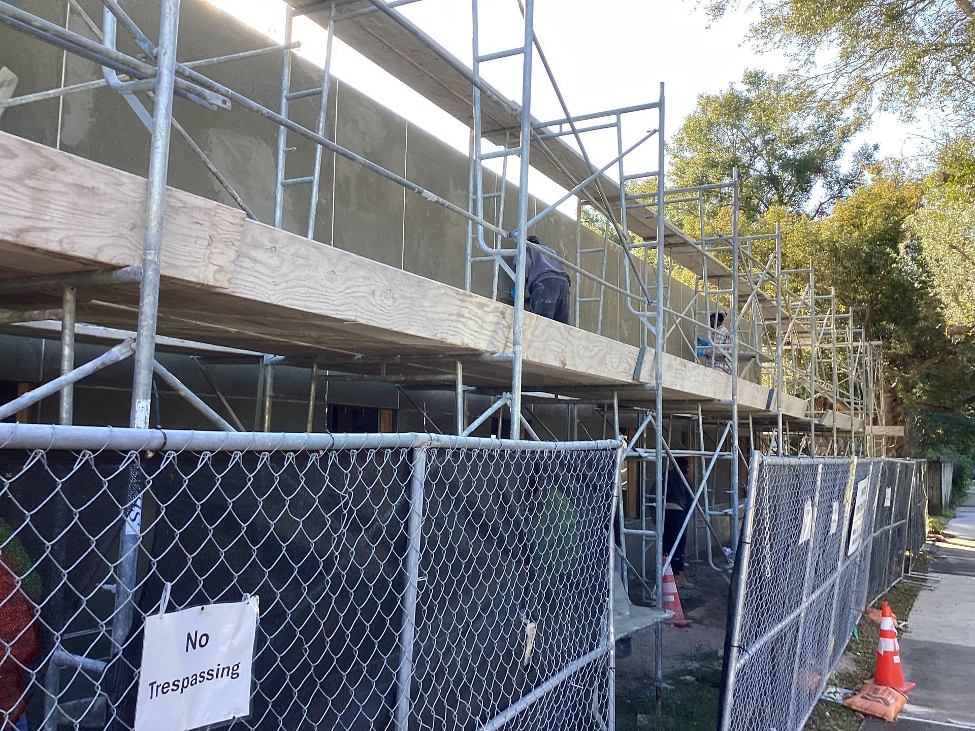 A construction site with scaffolding and a chain link fence.