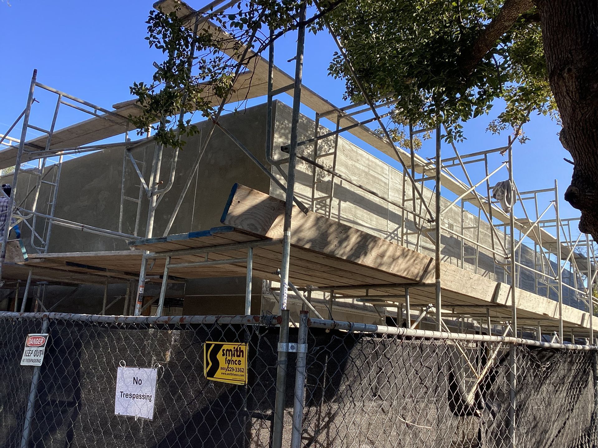 A construction site with scaffolding and a chain link fence