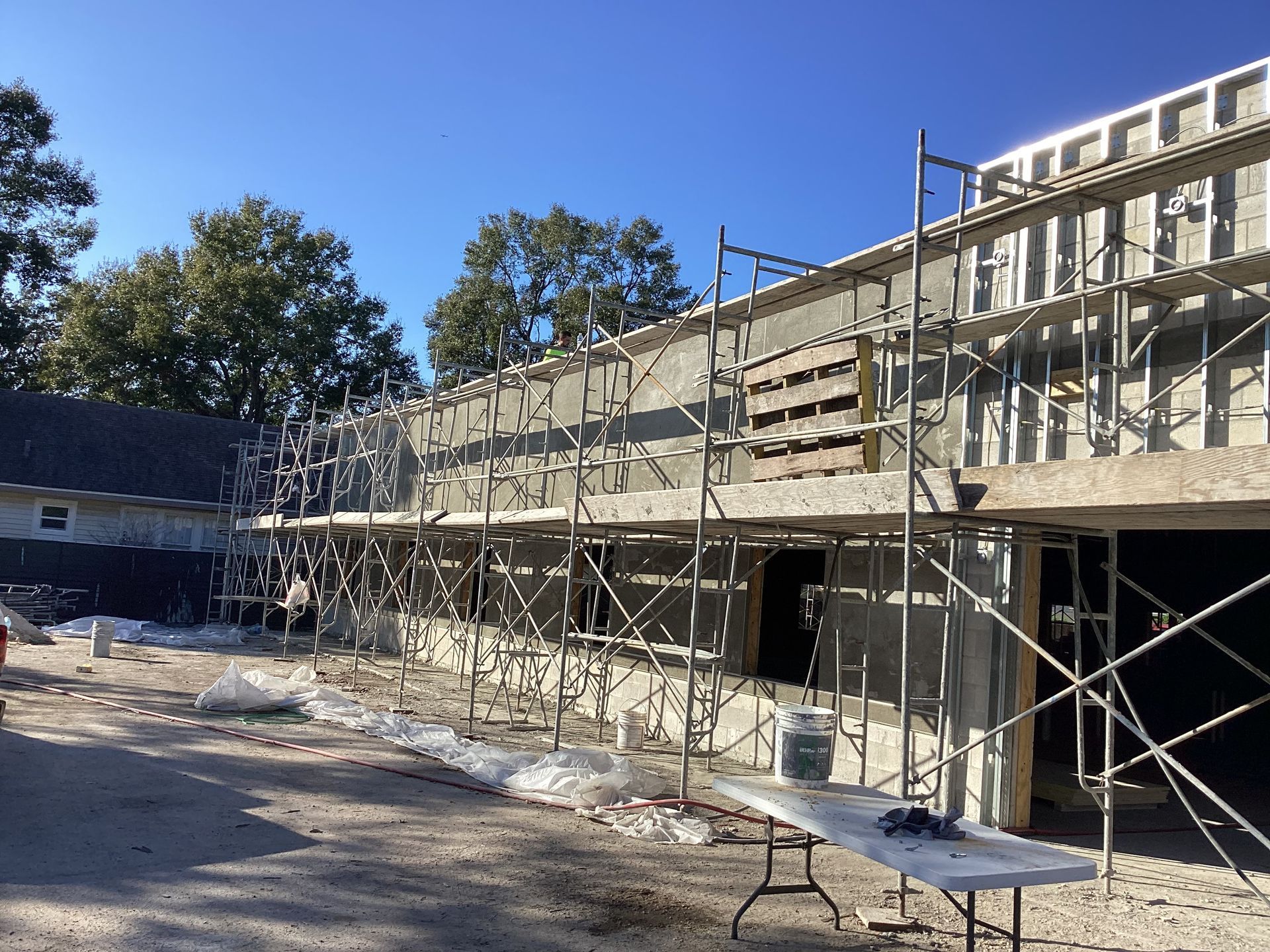 A building under construction with scaffolding and a table in front of it.
