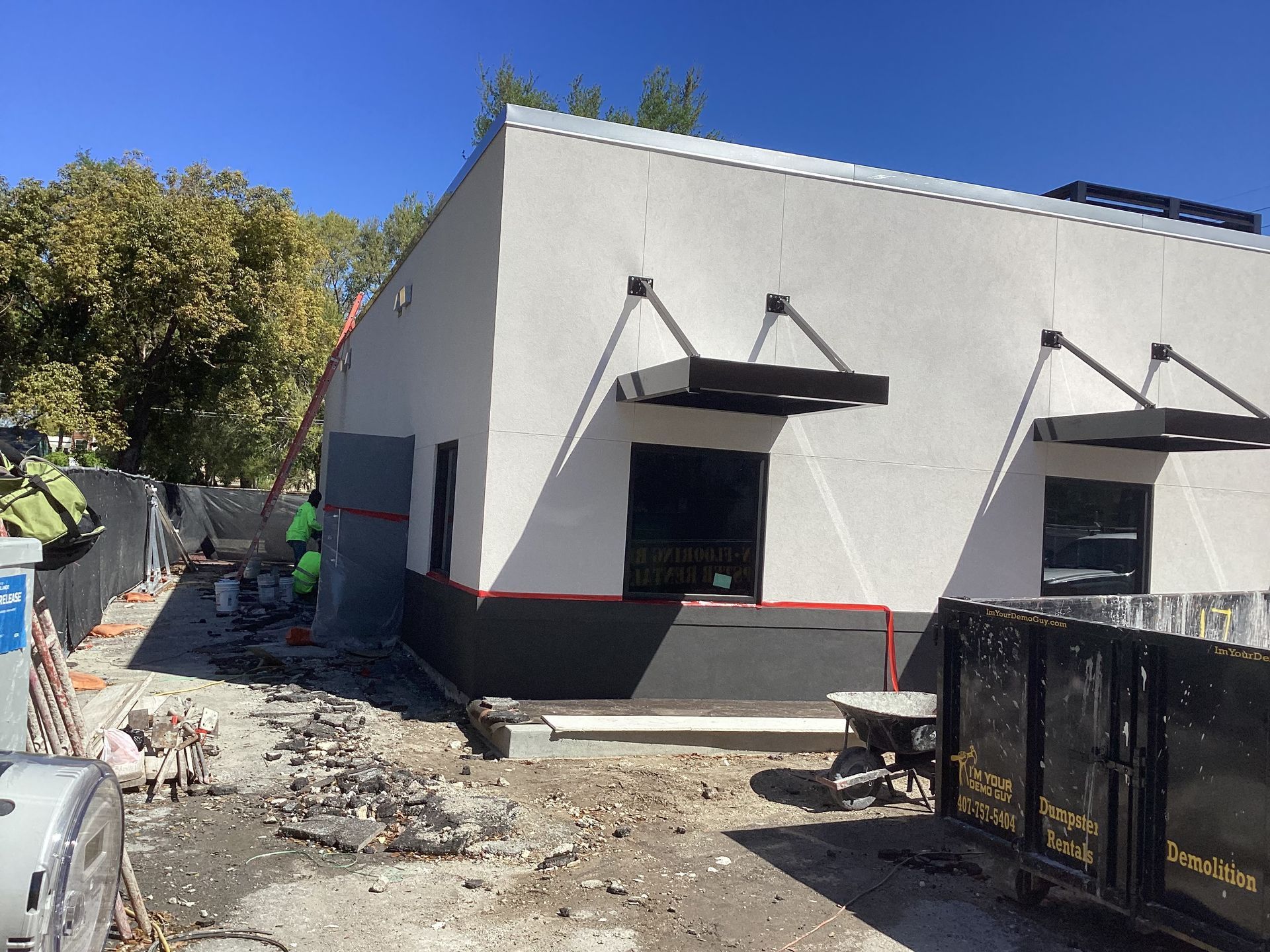 A building under construction with a dumpster in front of it.