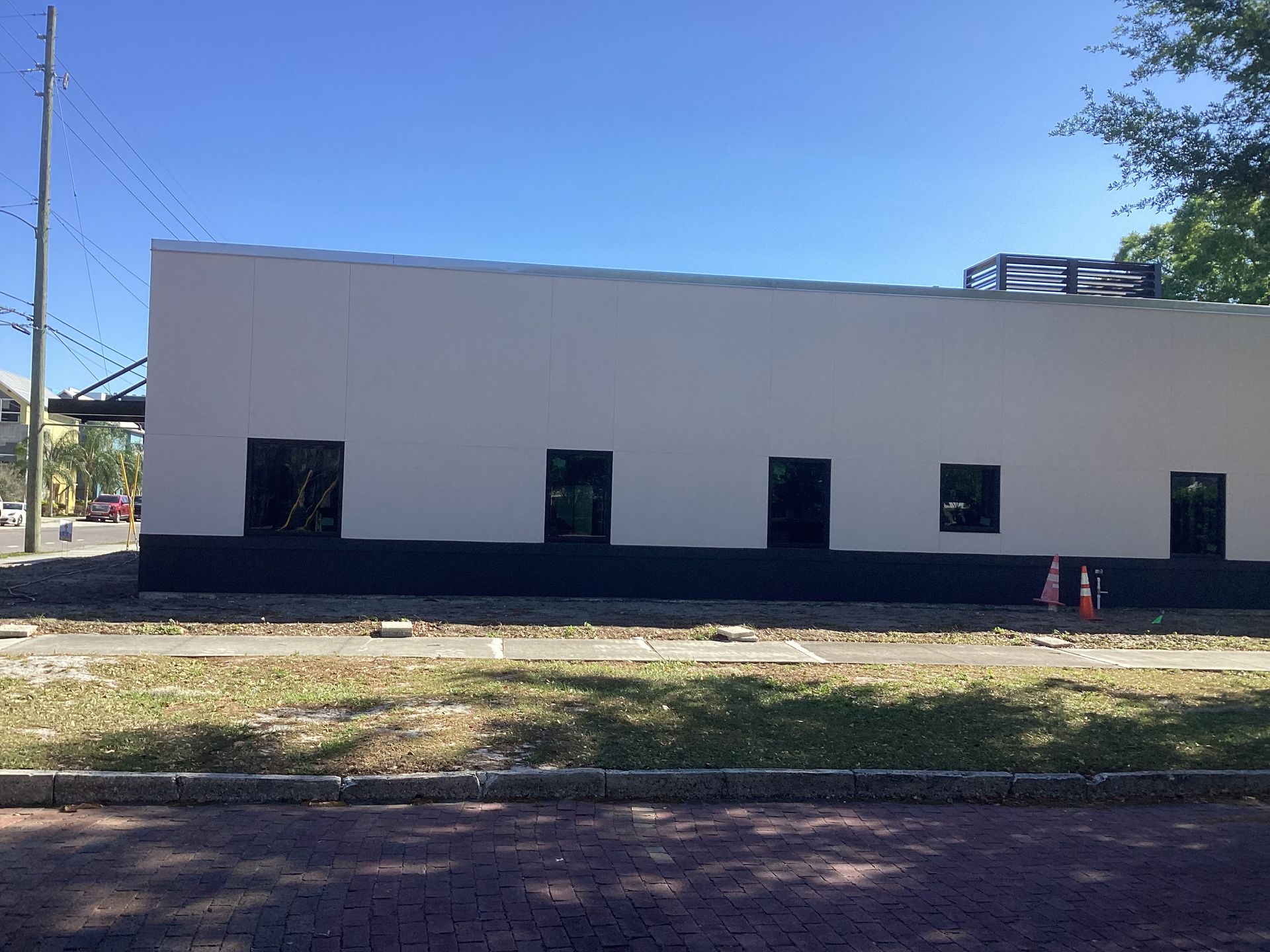 A large white building with black trim is being built on a sunny day.