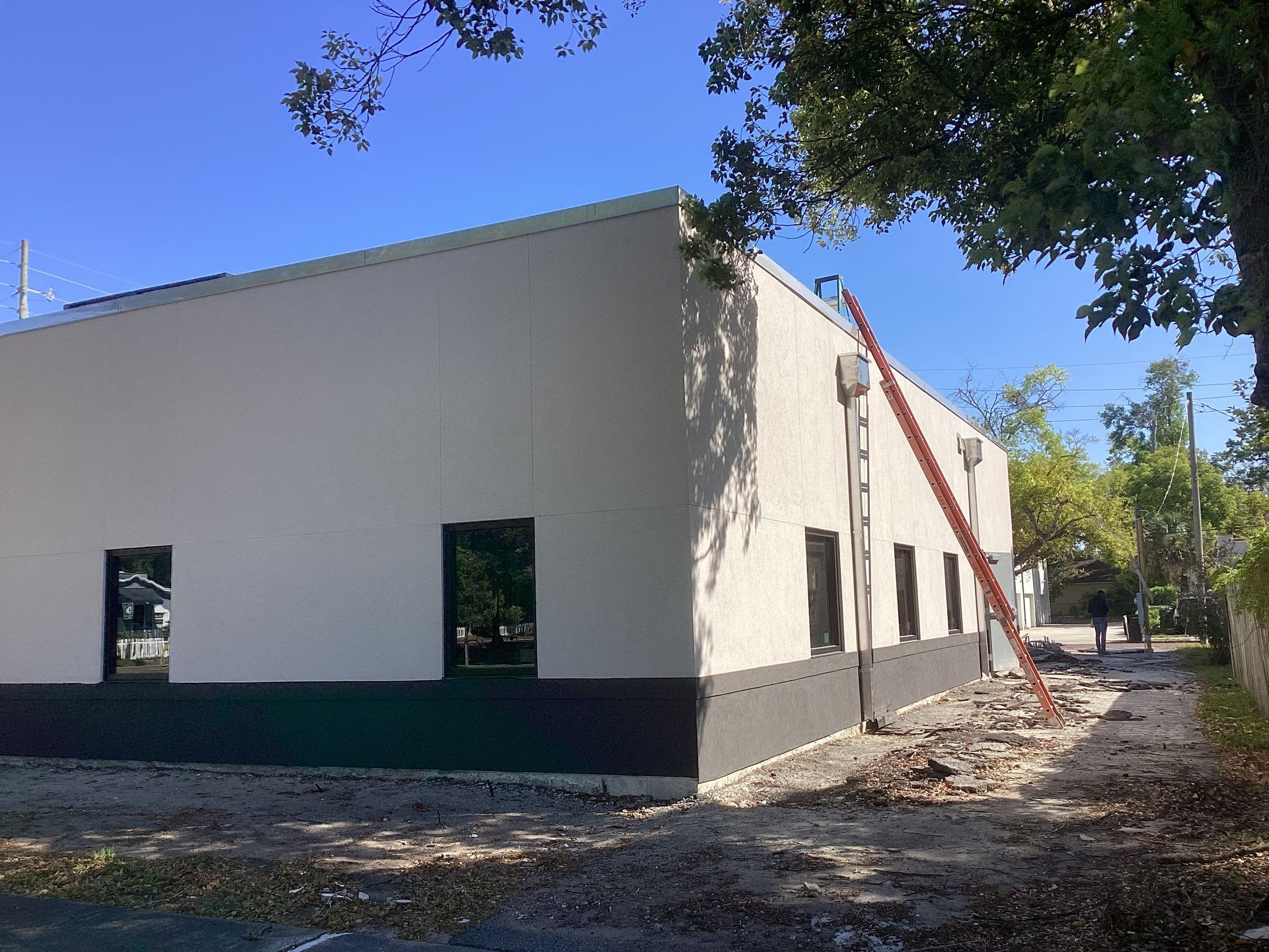 A white building with a red ladder attached to it is being painted.