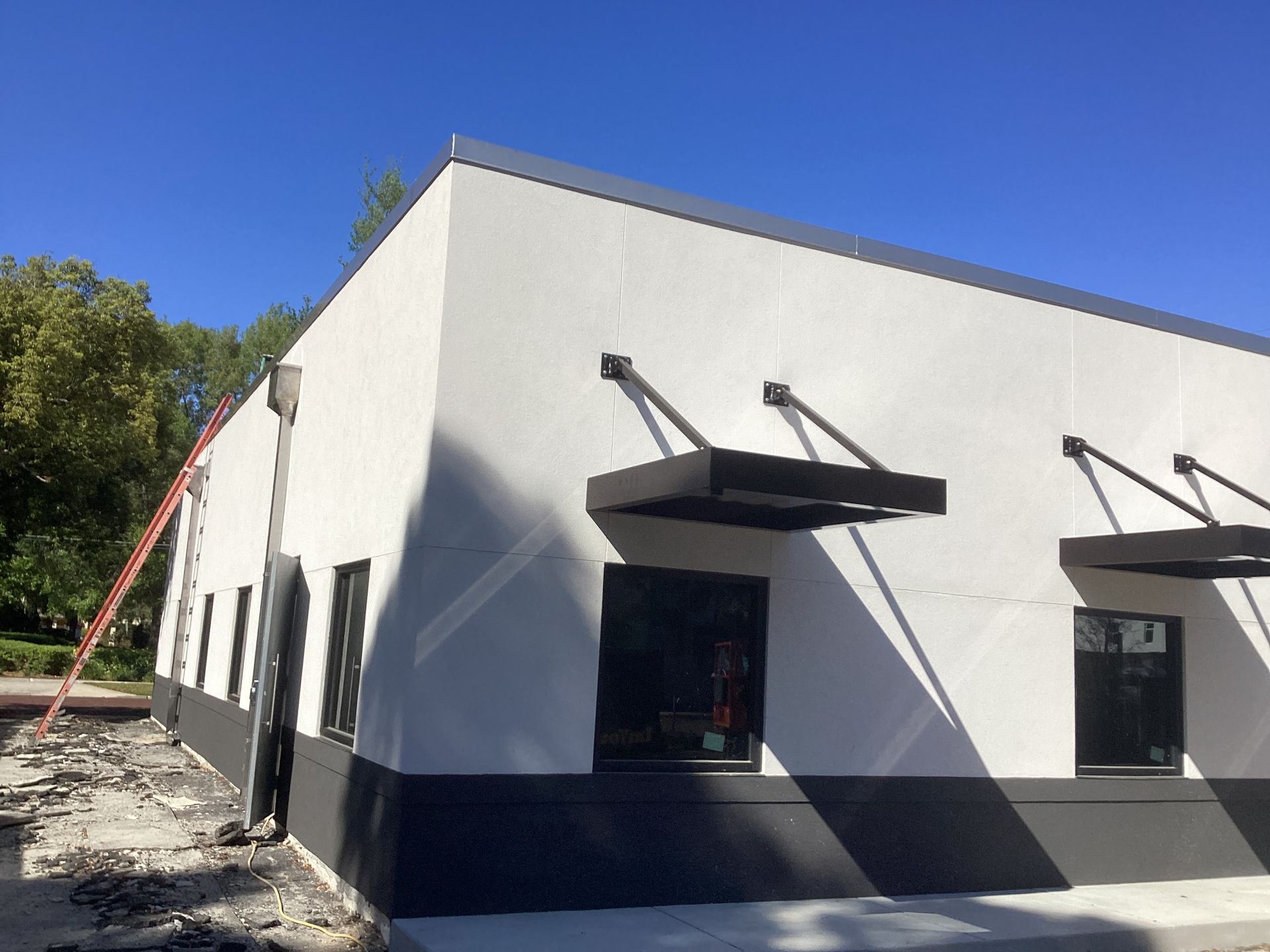 A white building with black trim and awnings on the windows