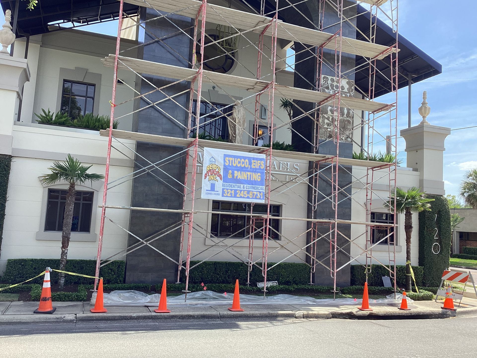 A building under construction with scaffolding and cones around it