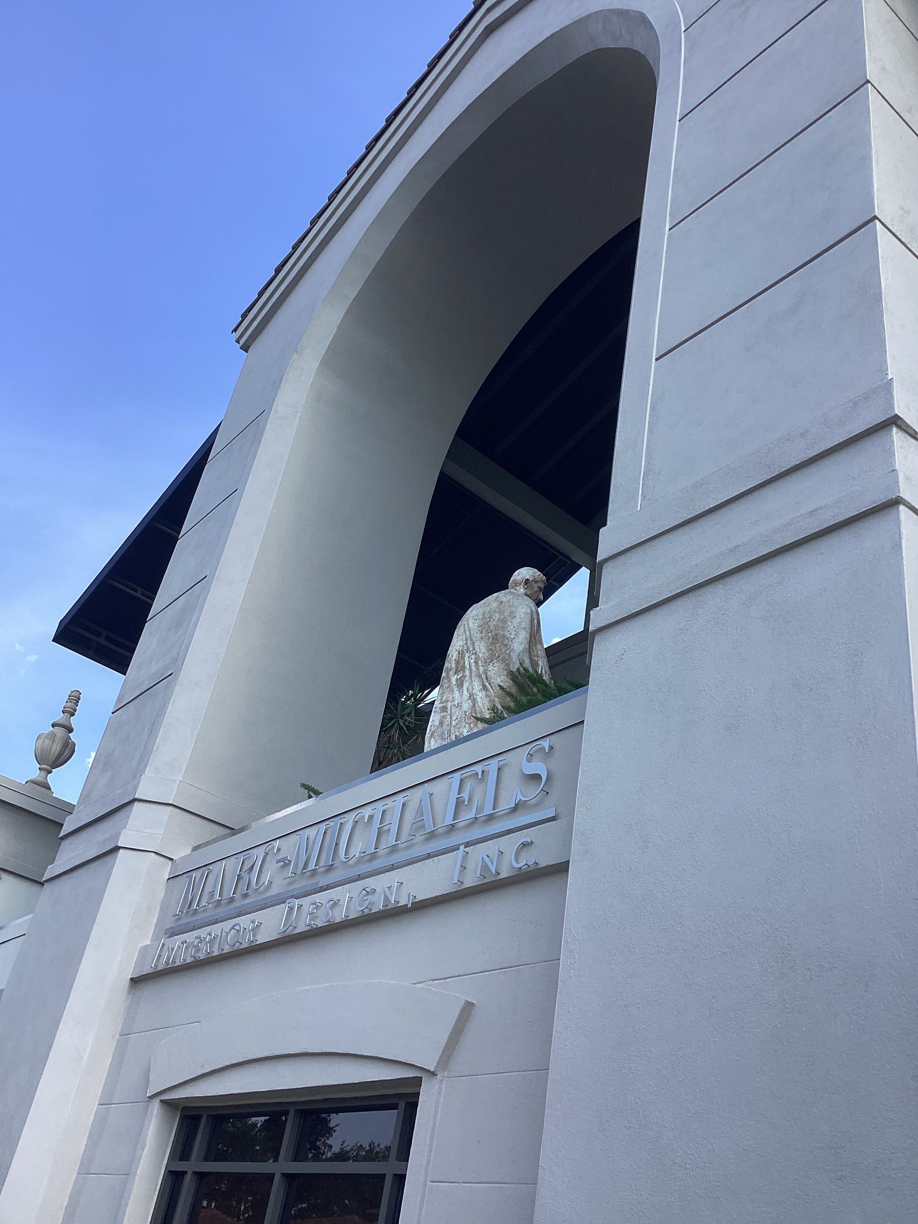 A white building with a statue of an eagle on the balcony