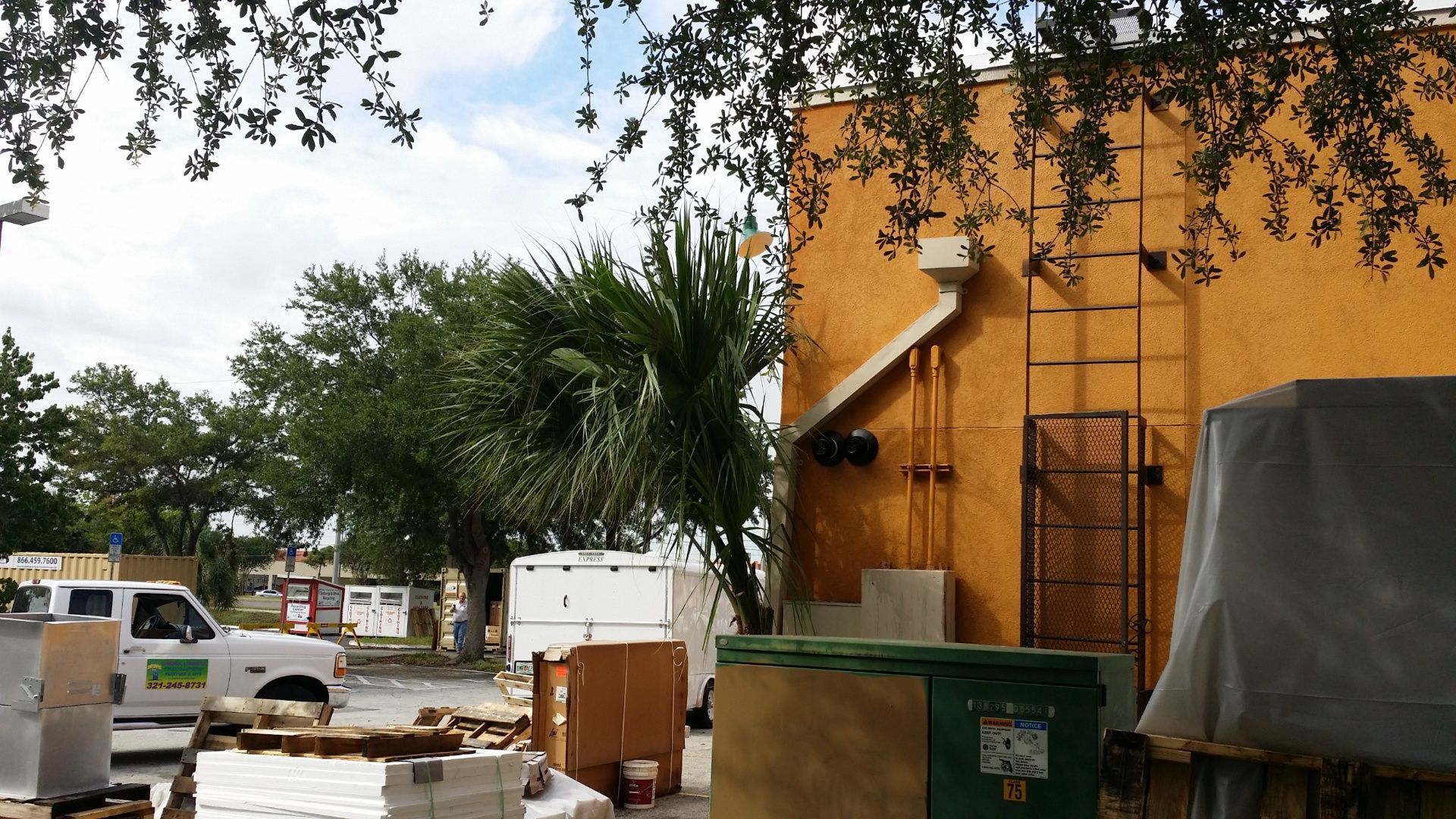 A white truck is parked in front of a yellow building