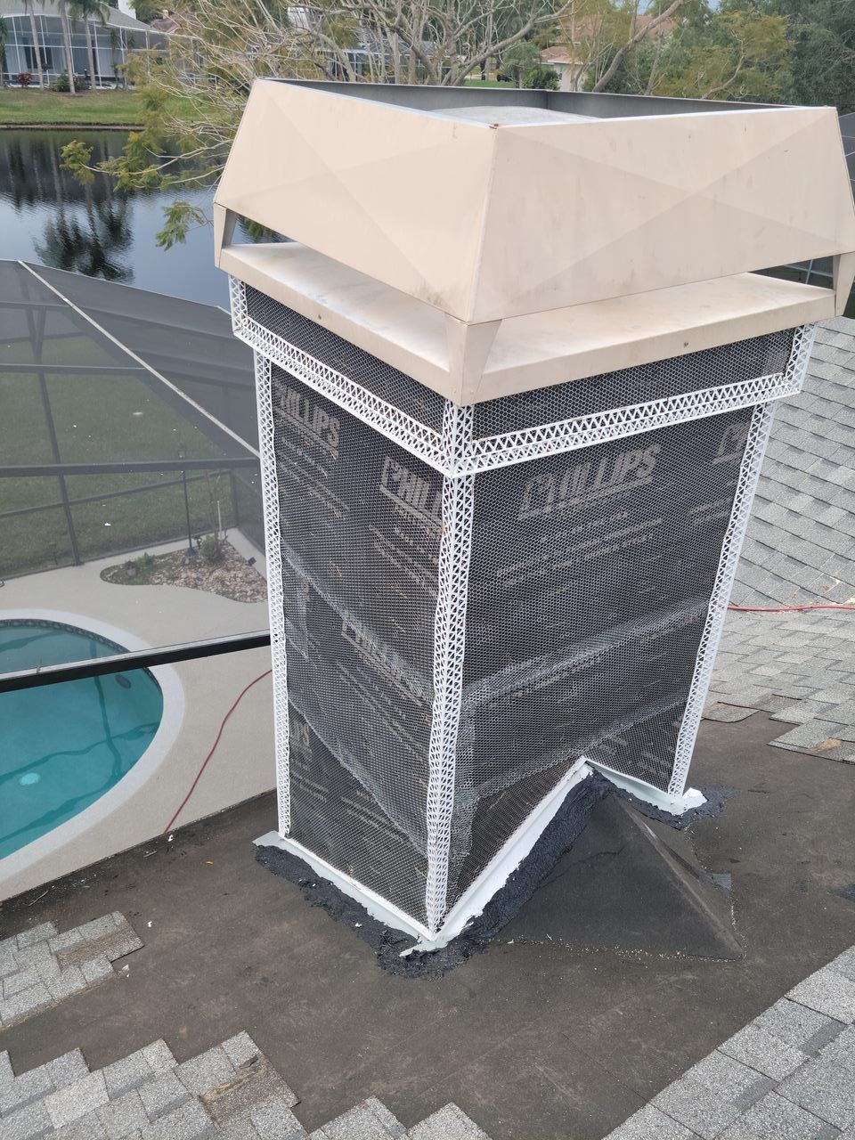 A chimney is sitting on top of a roof next to a pool.