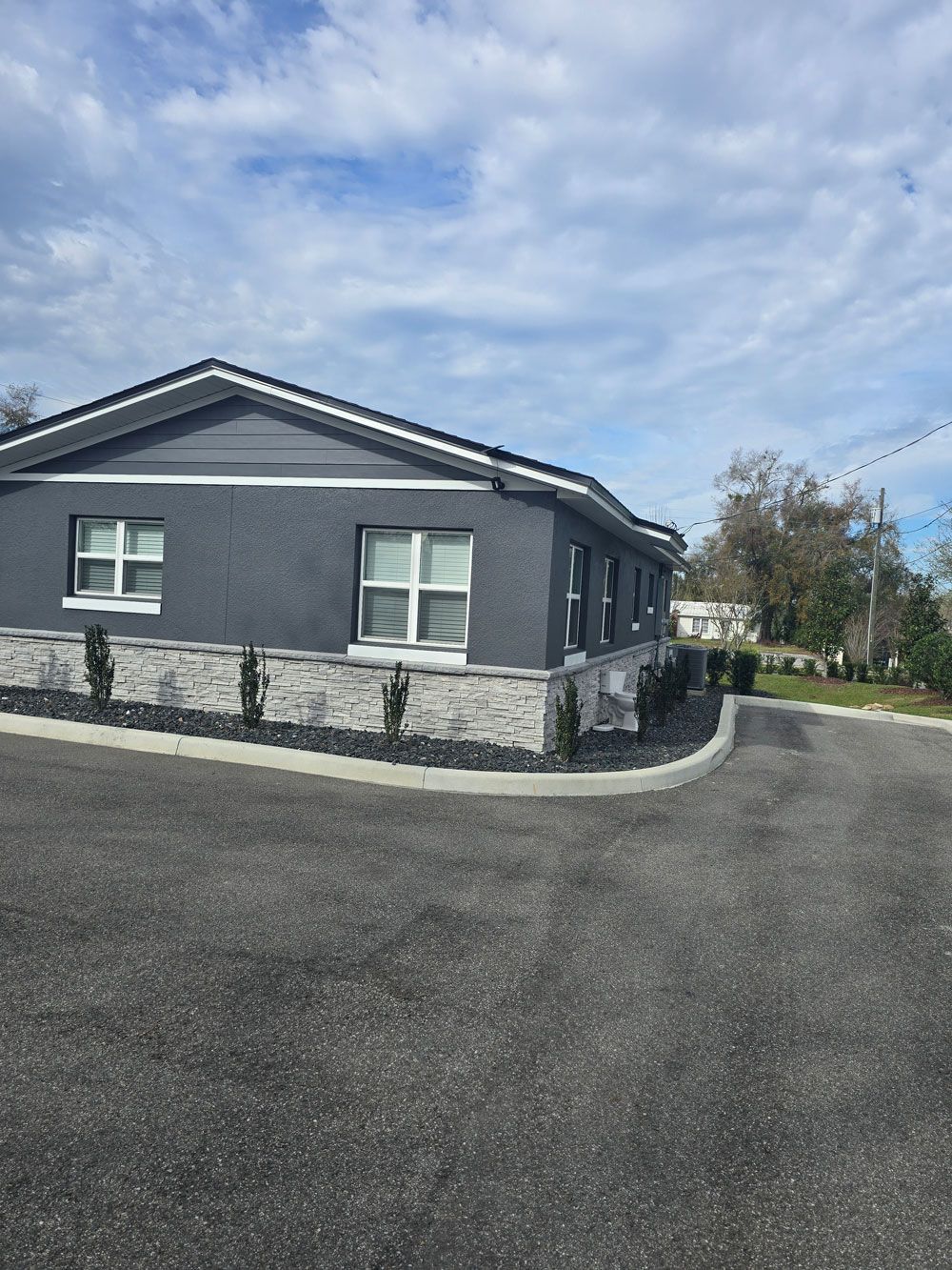 A dark gray building with a light brick facade and landscaping. 