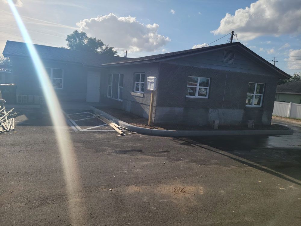 A gray building with white-framed windows and a ramp for accessibility on a sunny day.