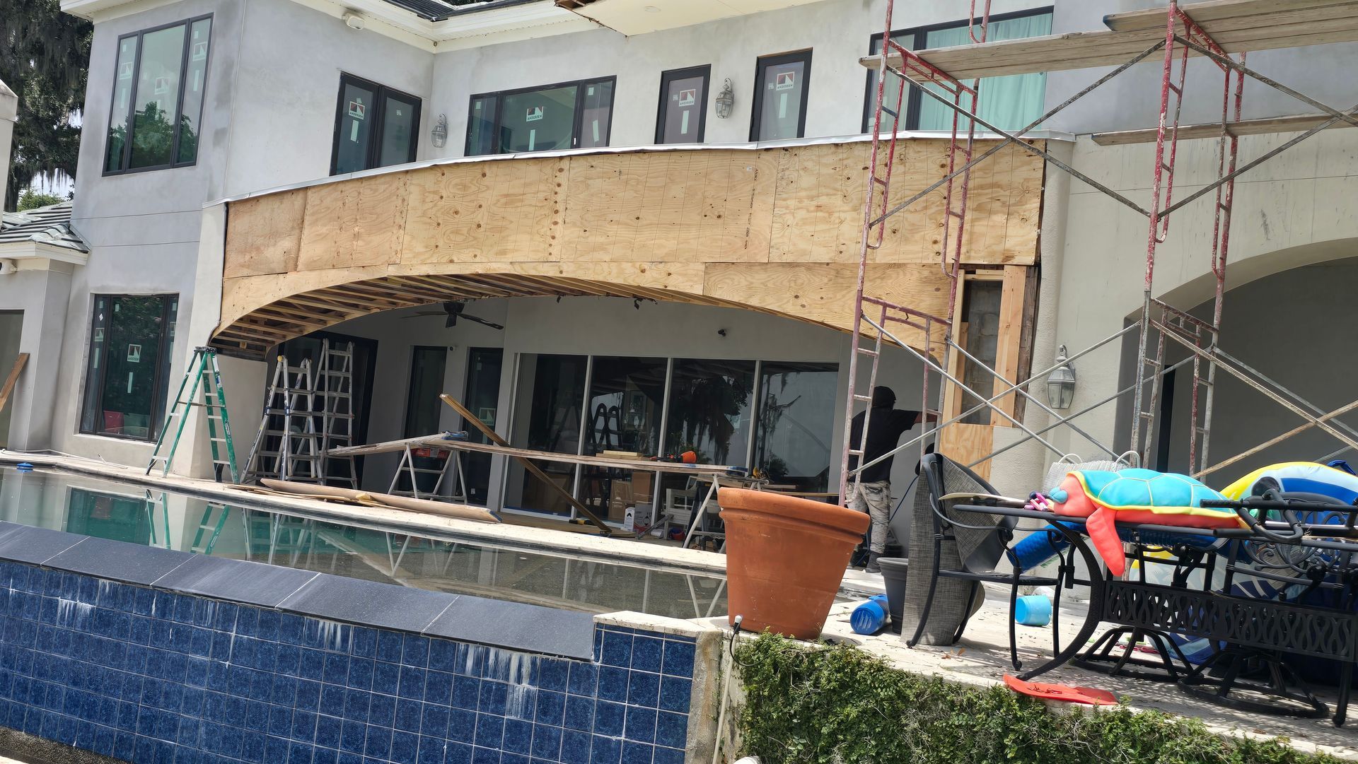 House under construction with a pool in the foreground. 