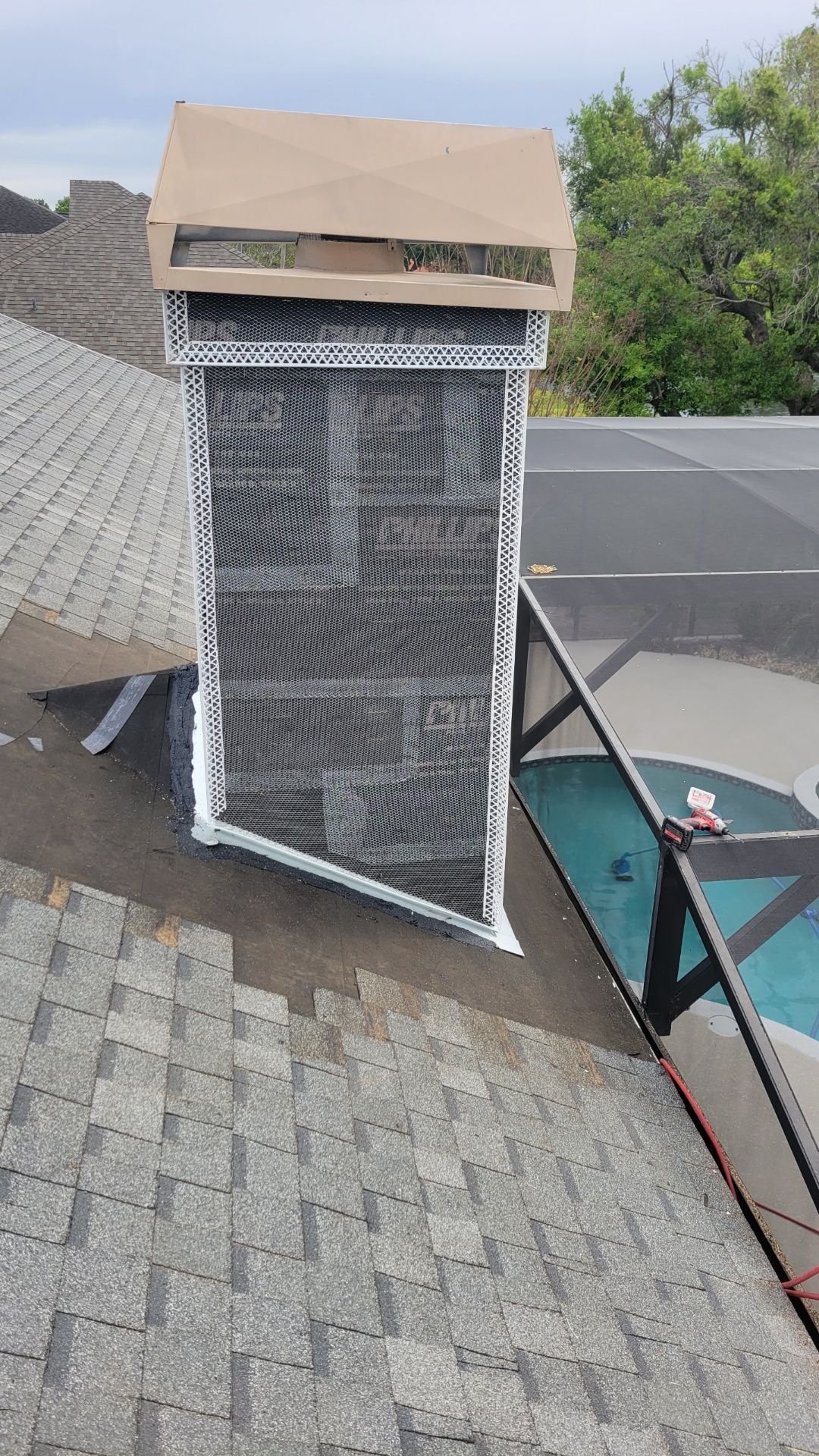 A chimney is sitting on top of a roof next to a pool.